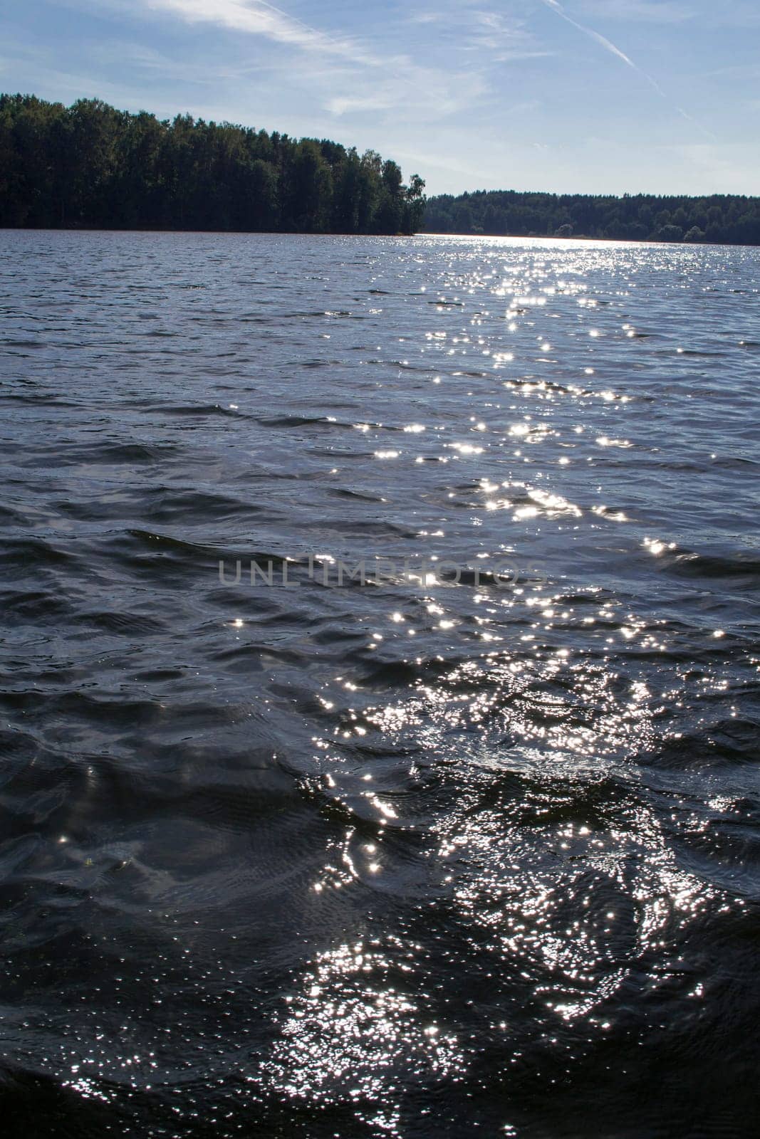 Sunlight twinkling of river water with small waves. Calm summer evening. Vertical image
