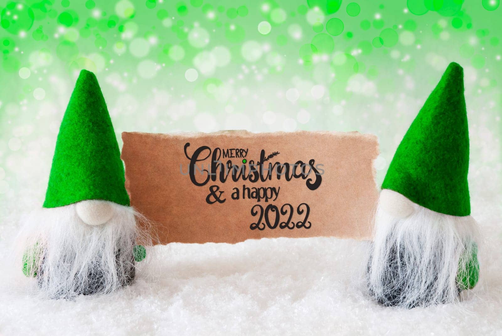 Sign With English Calligraphy Merry Christmas And A Happy 2022. Santa Claus With Green Hat. Snow With Green Sparkling Background