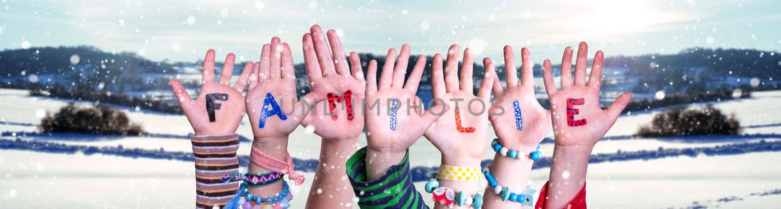 Children Hands Building Colorful German Word Familie Means Family. Snowy Winter Background With Snowflakes