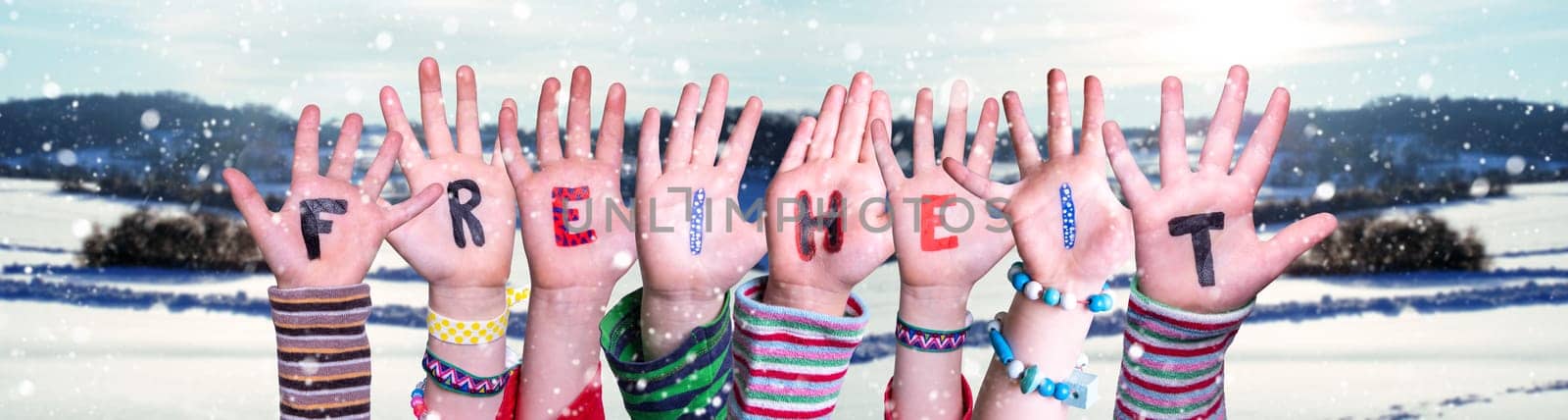 Children Hands Building Colorful German Word Freiheit Means Freedom. Snowy Winter Background With Snowflakes