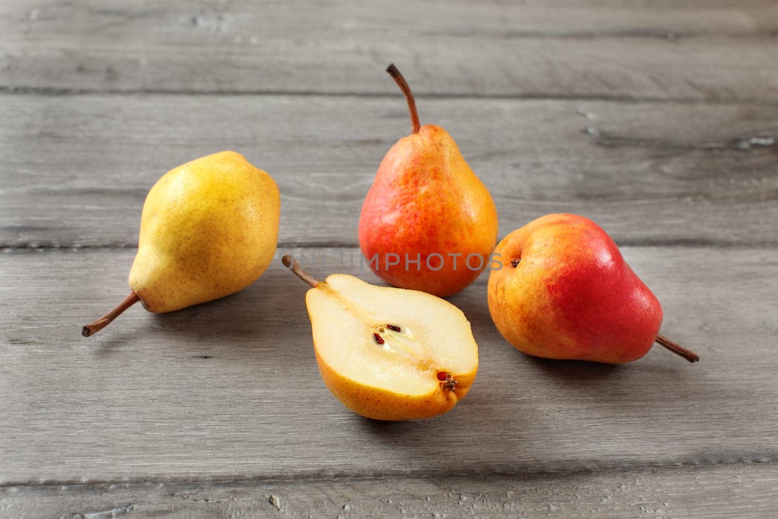 Four pears, one cut in half, on gray wood desk.