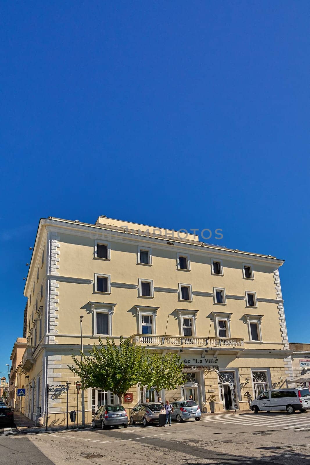 Civitavecchia. Italia - December 17, 2024: Elegant facade of Hotel De La Ville in Civitavecchia classic architecture and yellow exterior on a busy street Concept: Urban hospitality and architecture