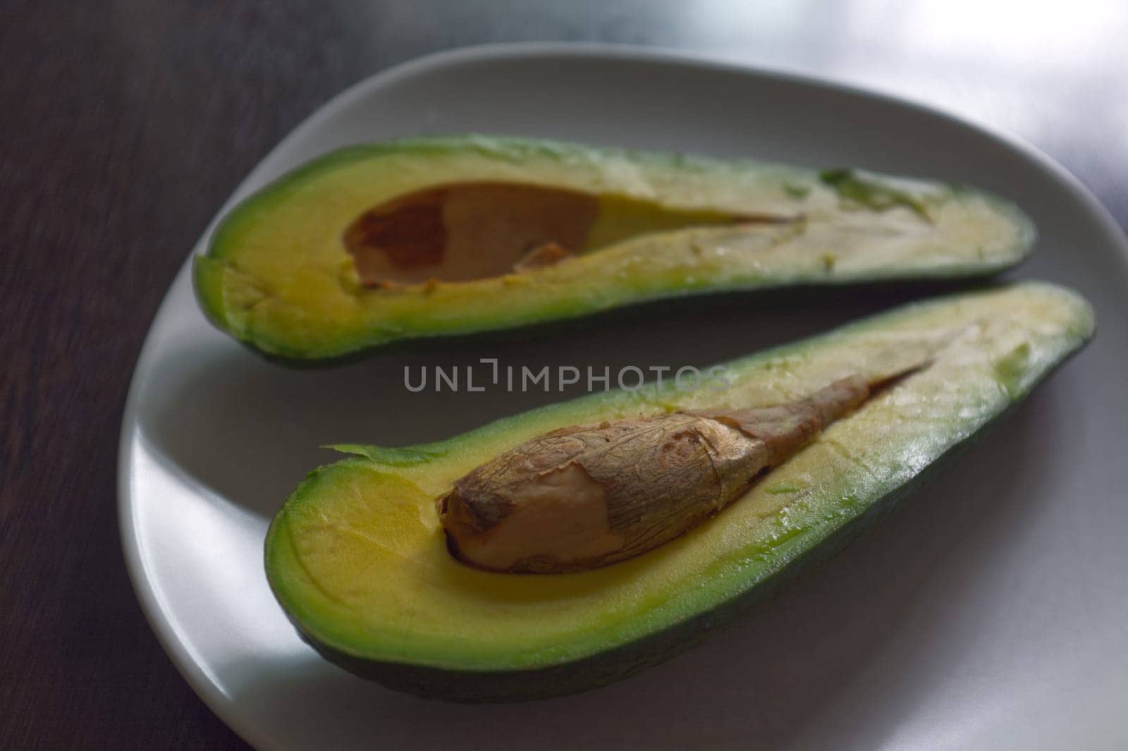 Avocado split in half, isolated on a black background