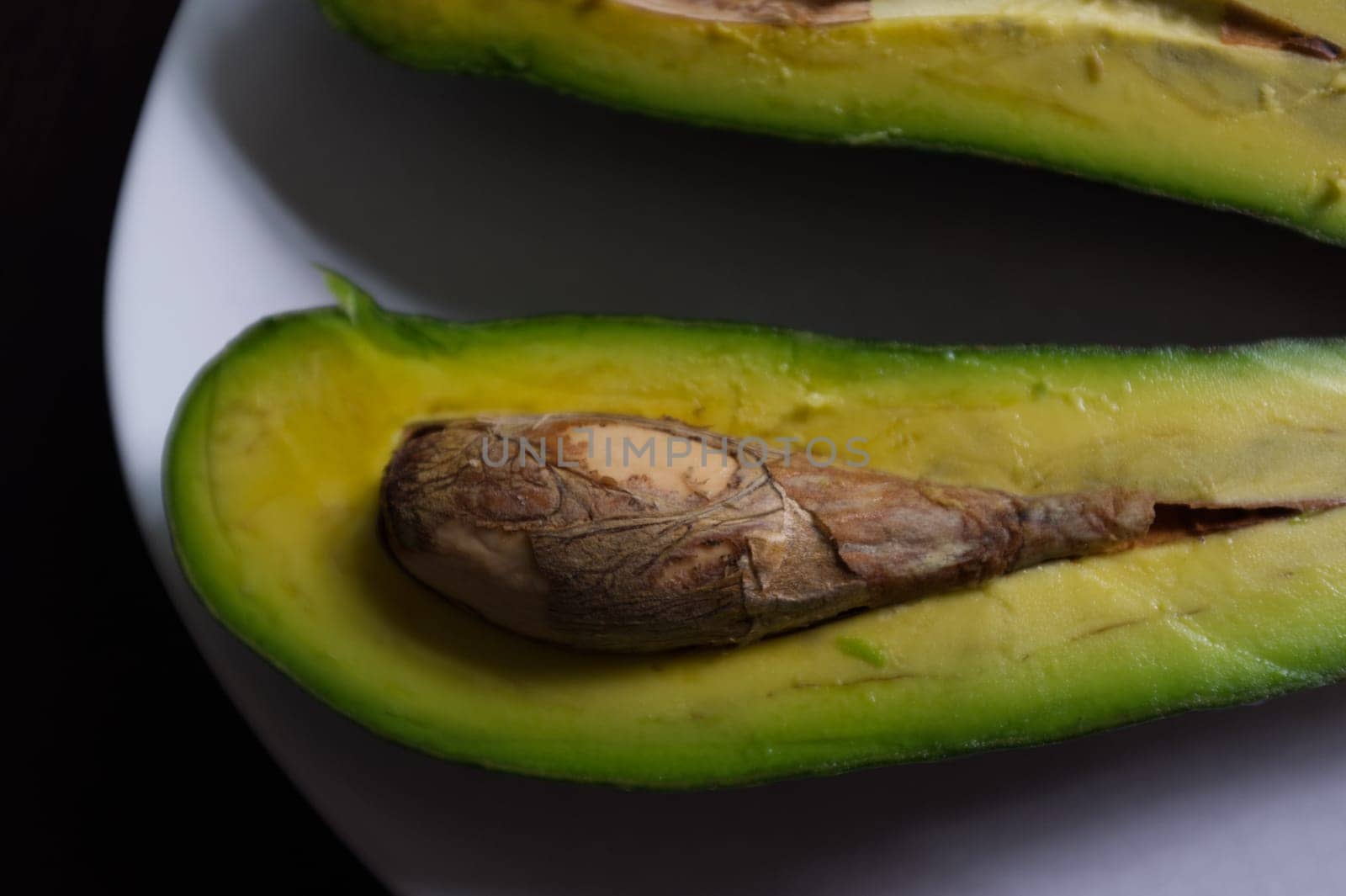 Avocado split in half, isolated on a black background
