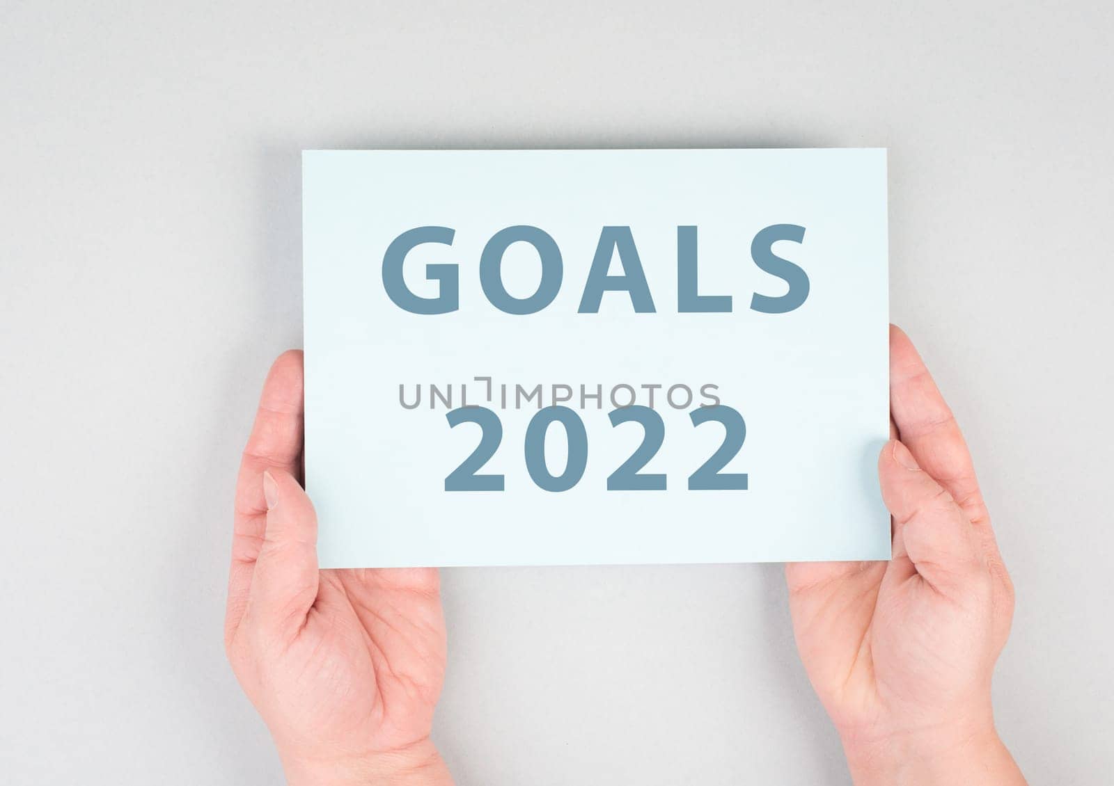 Goals 2022 is standing on a paper, hands are hold in the message, planning new achievements for the new year