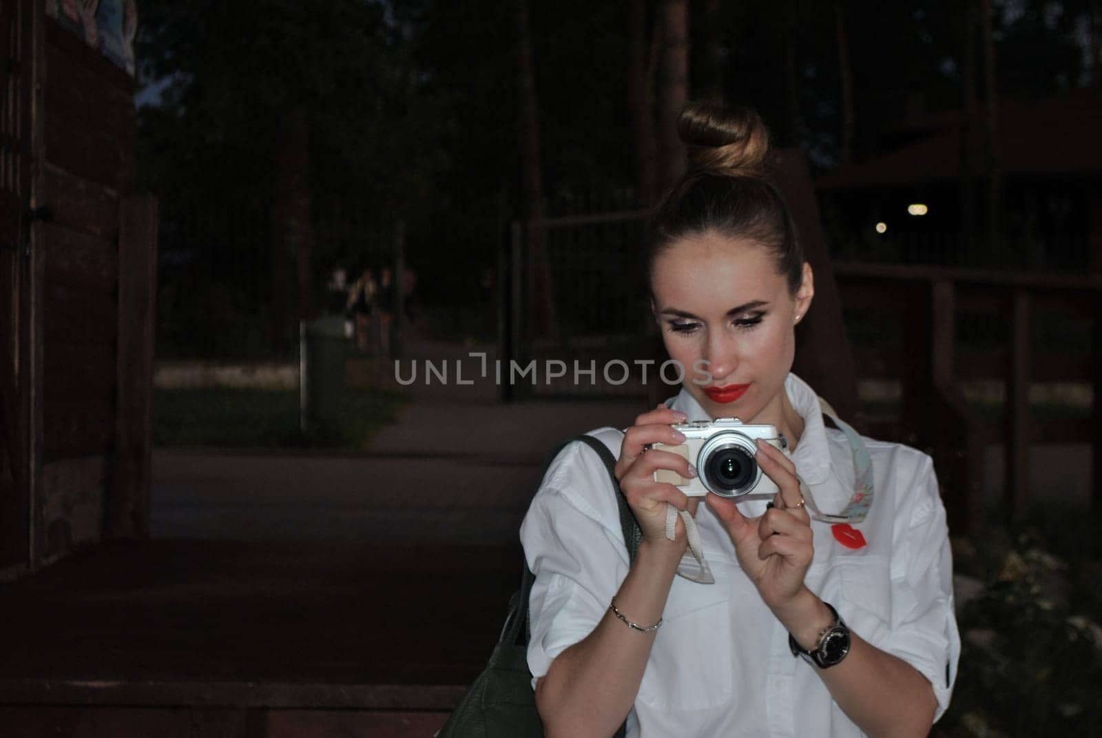 portrait of the young woman taking pictures on a white camera in the evening