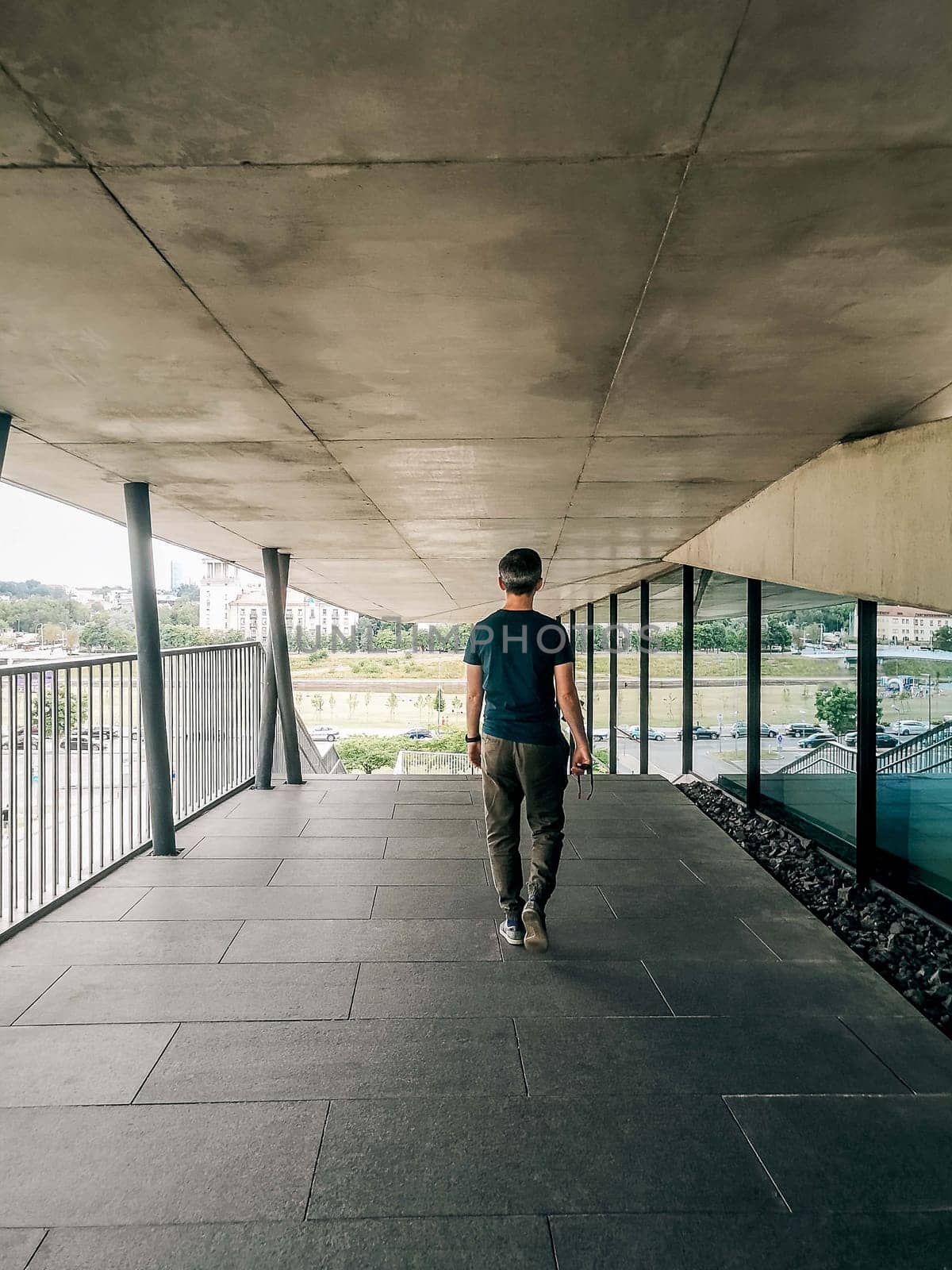 A man walks down the outer corridor of the building