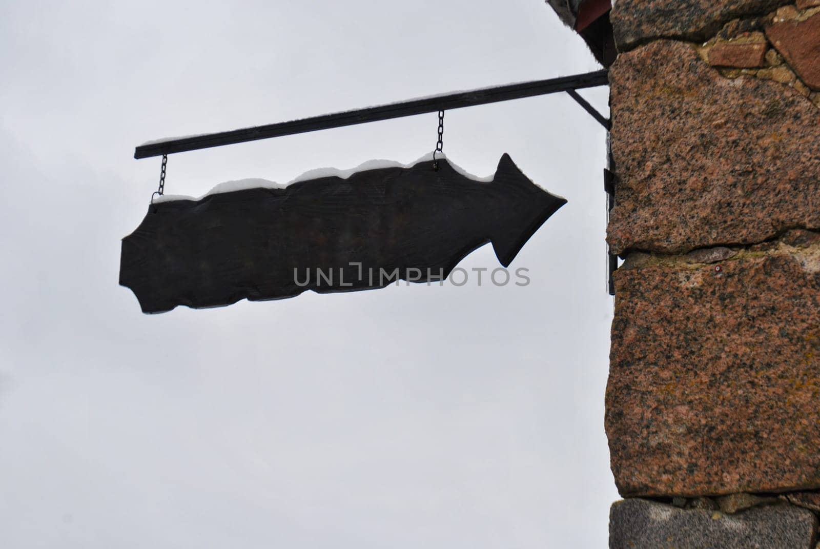 An old-style pointer hangs on the wall of the building against the sky, free space for text