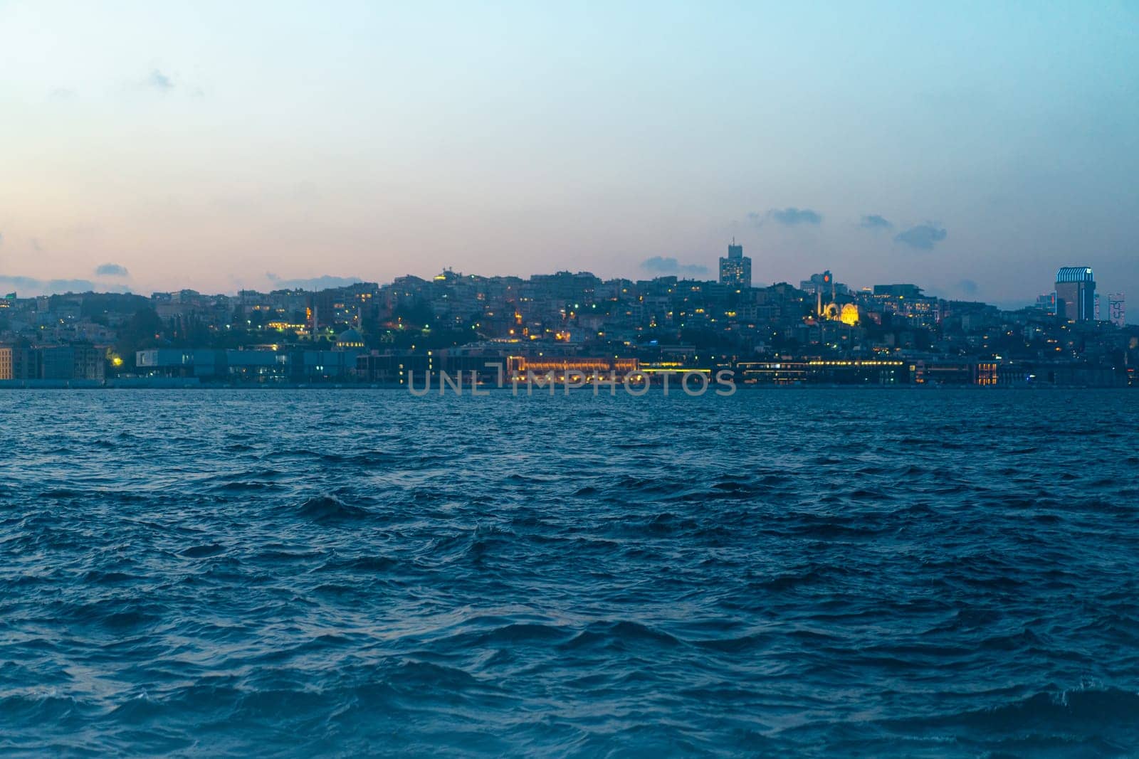 sunset panorama of the Istanbul city skyline over the Golden Horn with Bosphorus waves in the foreground