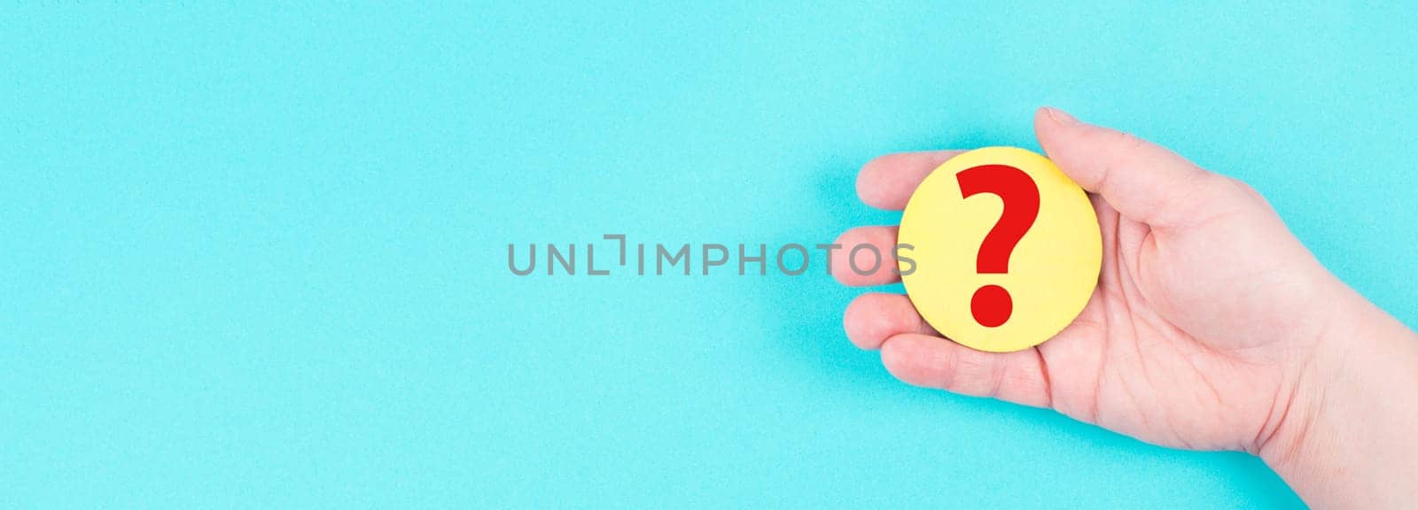 Woman holds a red question mark in her hand, blue background, copy space for text, finding answers