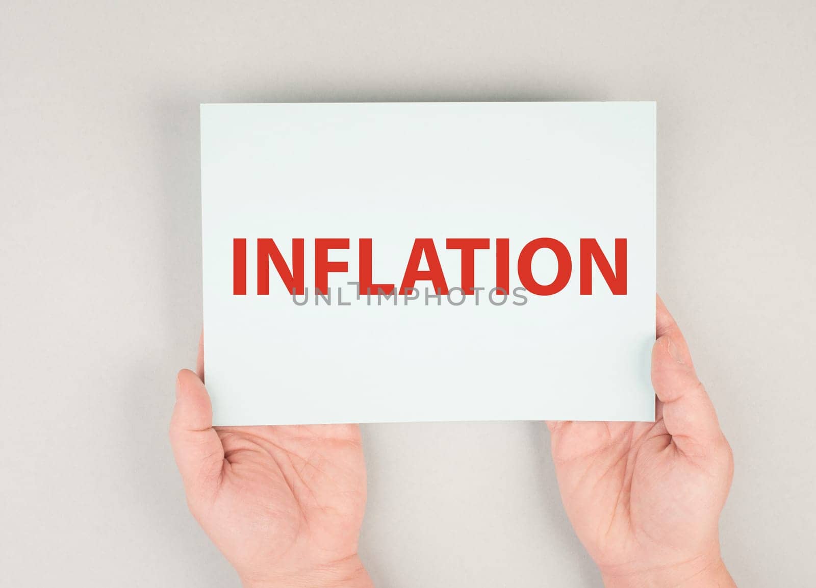 The word inflation is standing on a paper, increasing living costs, hands hold message