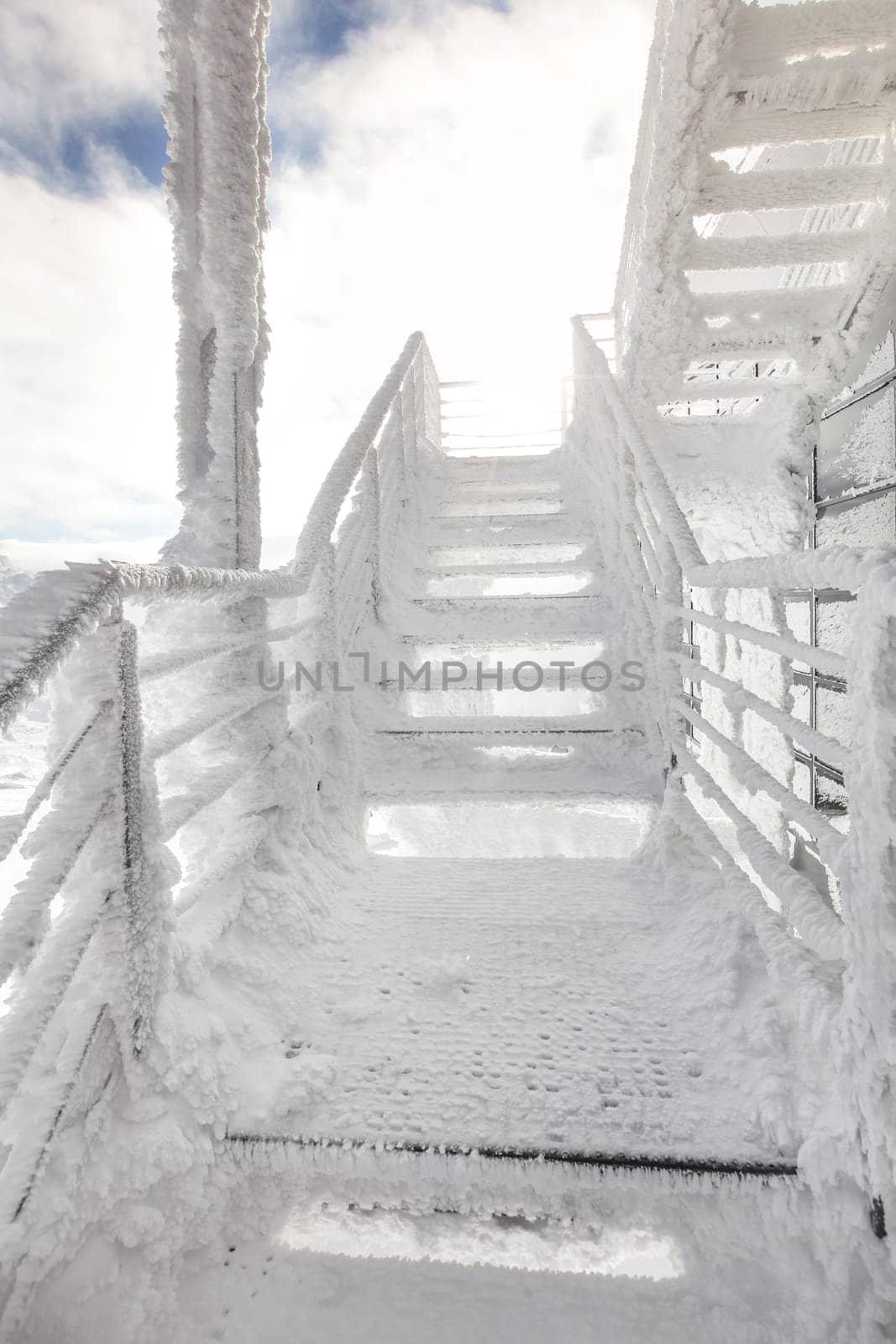 Stairs and rail, completely covered with ice crystals, strong sun back light in background. Freezing winter.