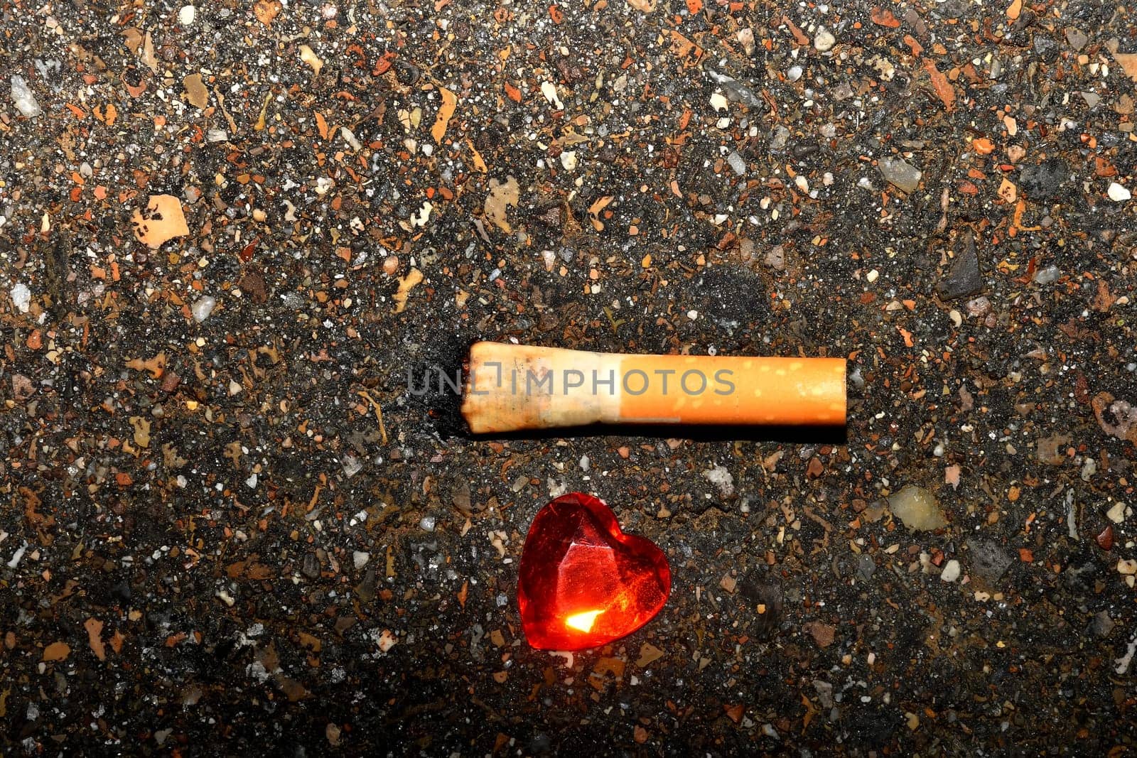 Heart on a street floor with cigarette butt
