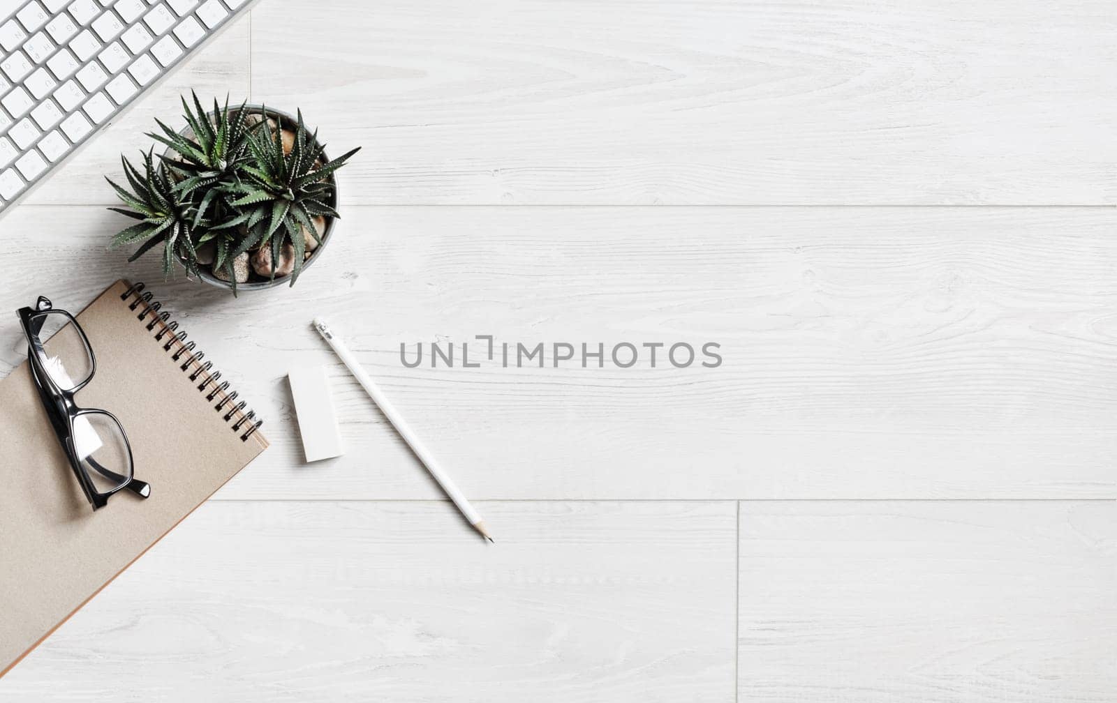 Wooden background with stationery. Overhead above view photo of notebook, succulent plant, glasses, pencil, eraser and keyboard. Copy space for your text. Flat lay.