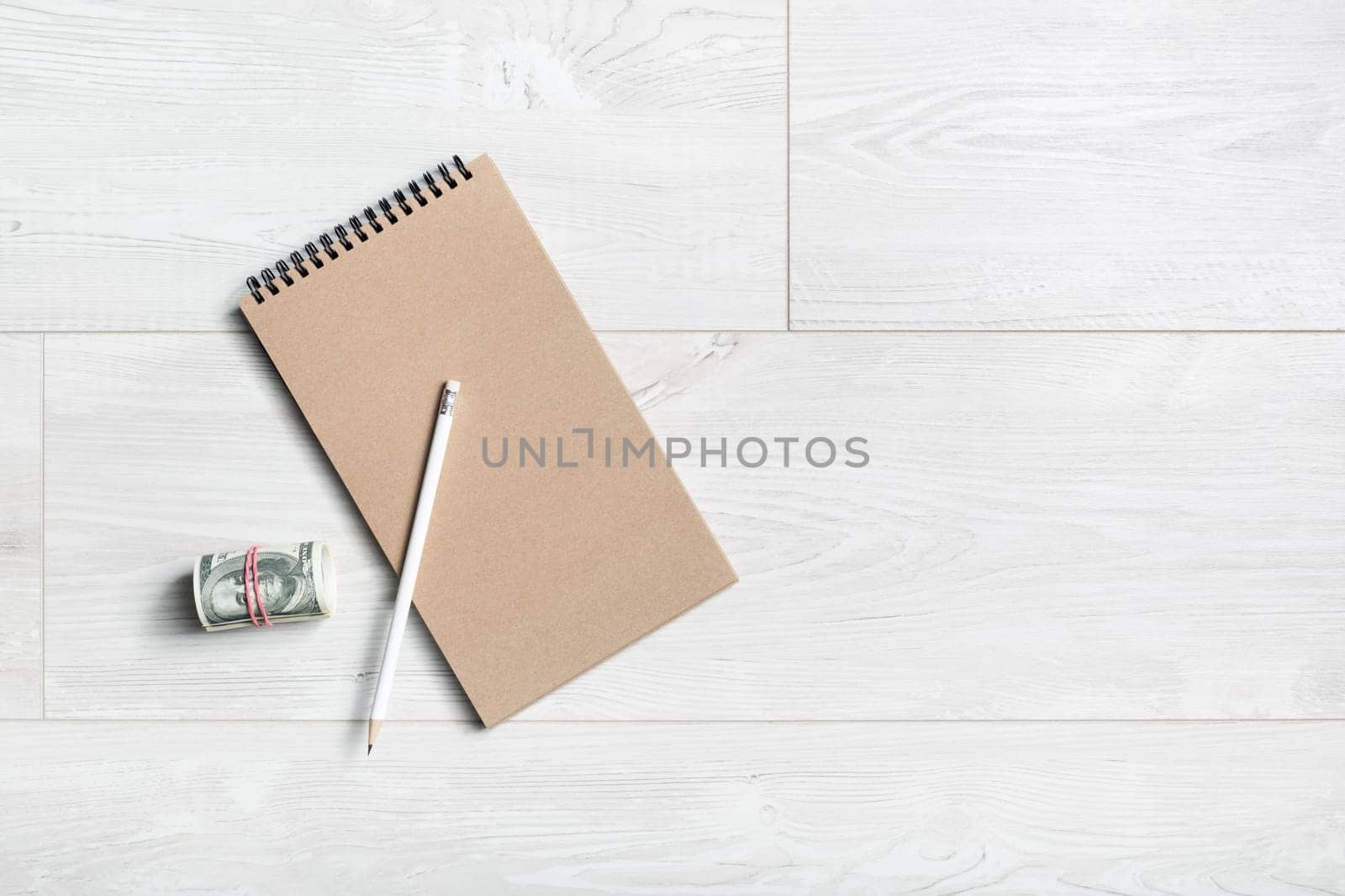 Notepad, pencil and money on wooden background. Flat lay.