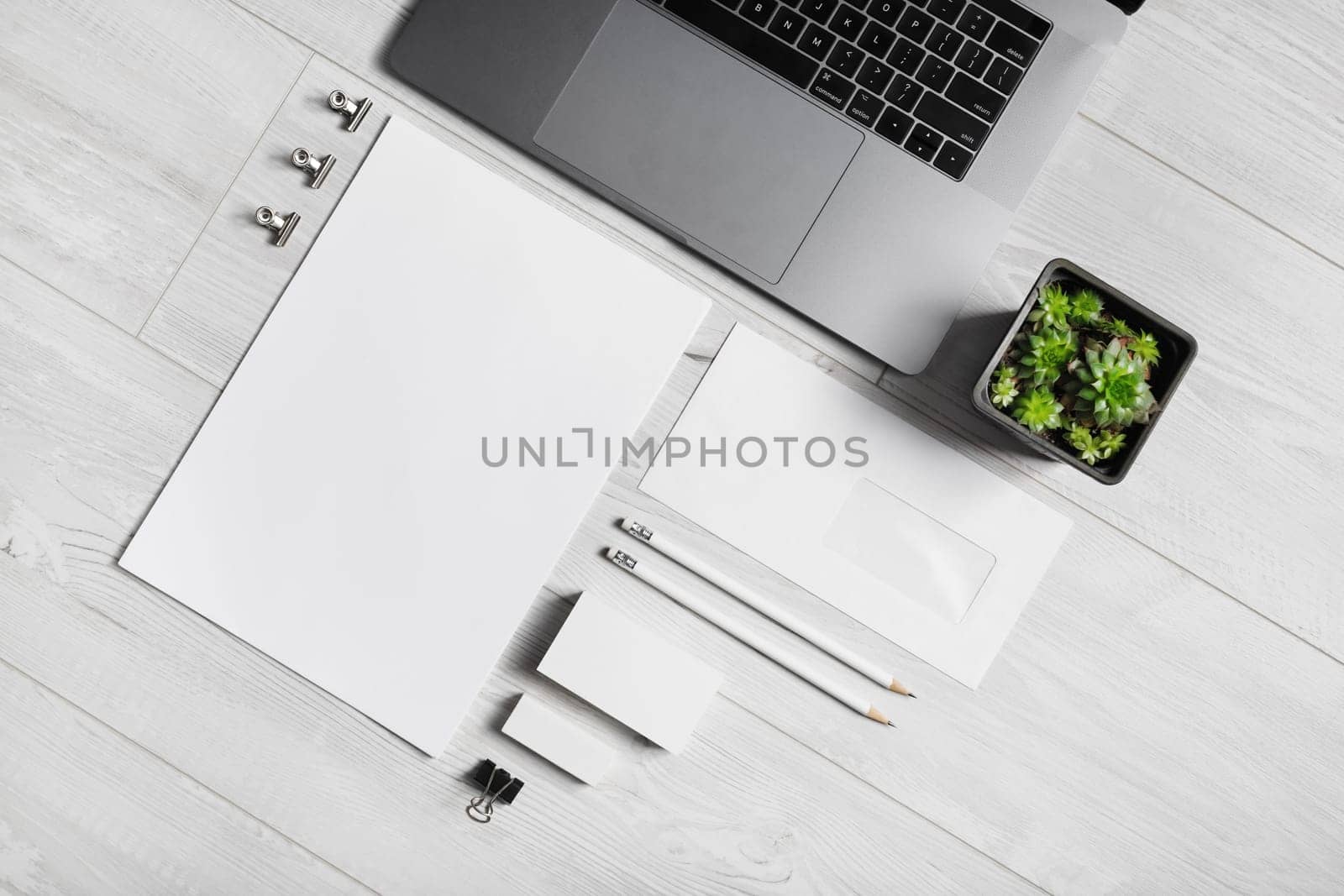 Blank branding stationery set and laptop on wooden background. Corporate identity mockup. Flat lay.