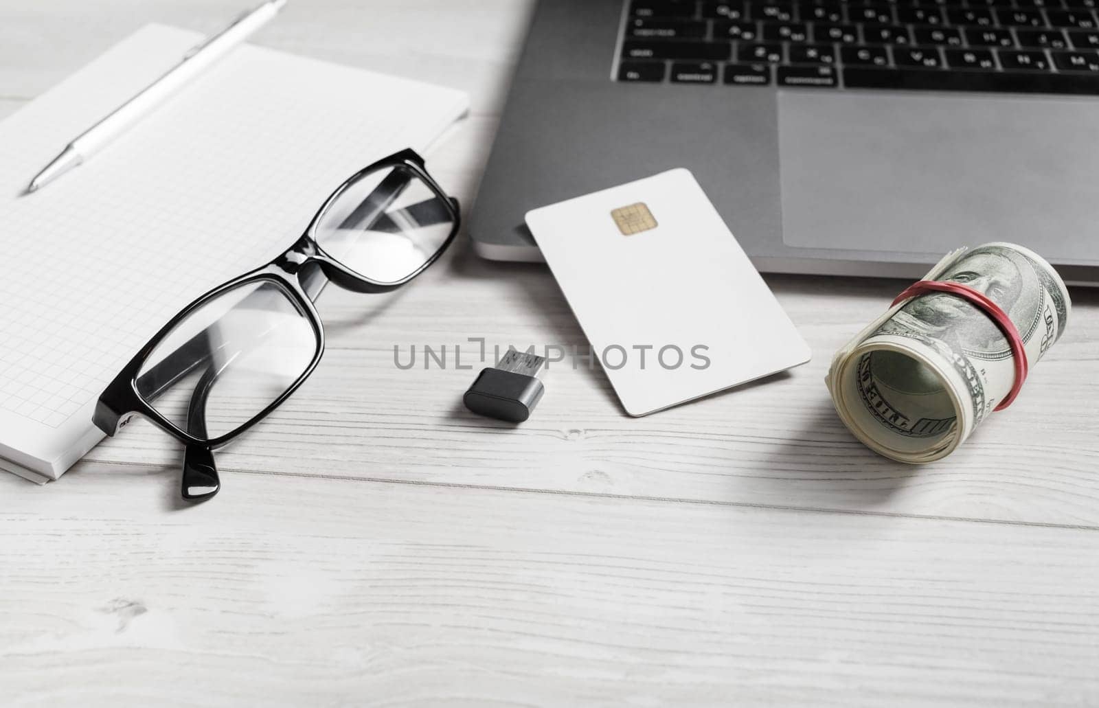 Online shopping and paying concept. Dollars, credit card, glasses, flash drive and laptop keyboard.