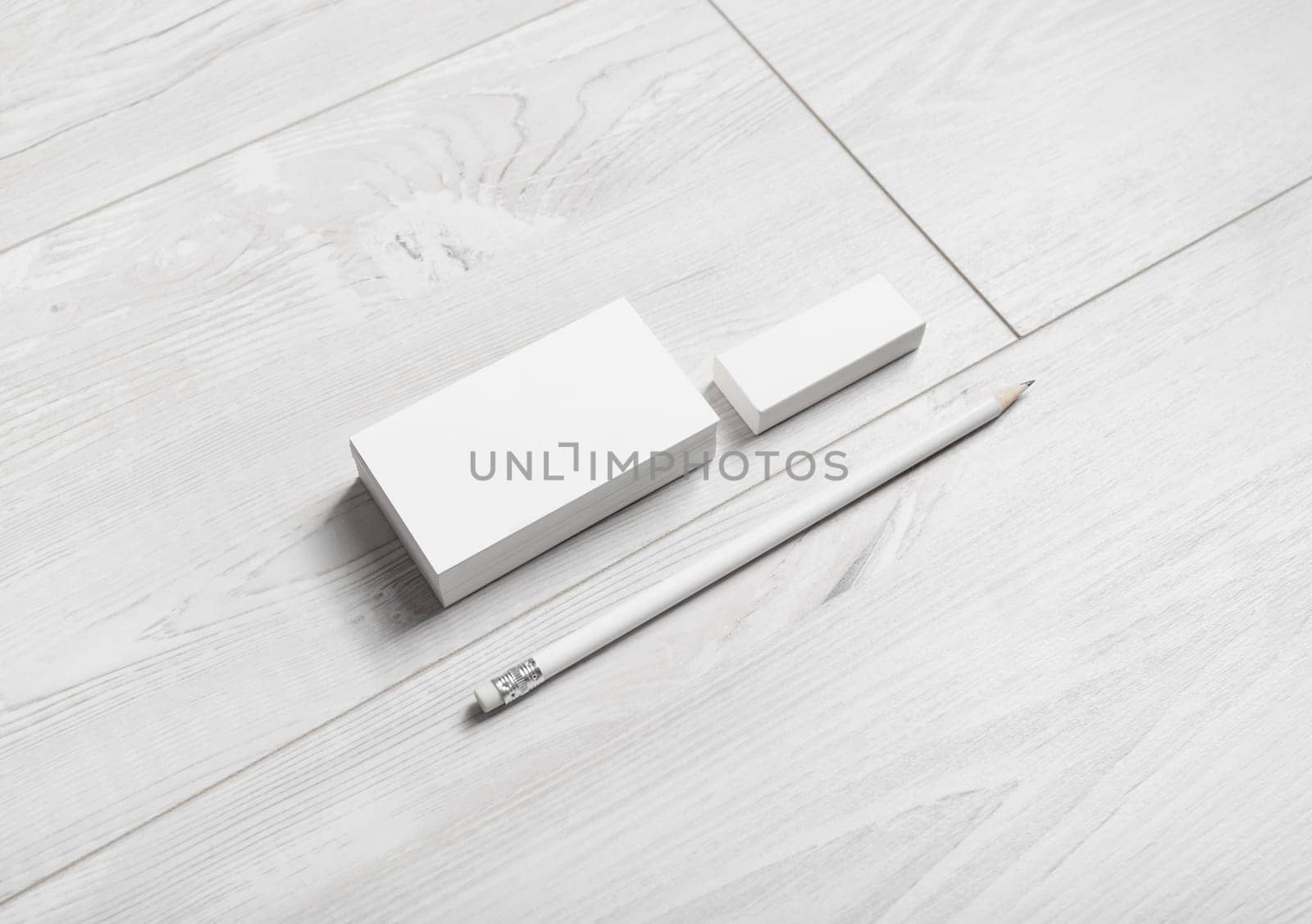 Photo of blank business cards, pencil and eraser on wooden background.