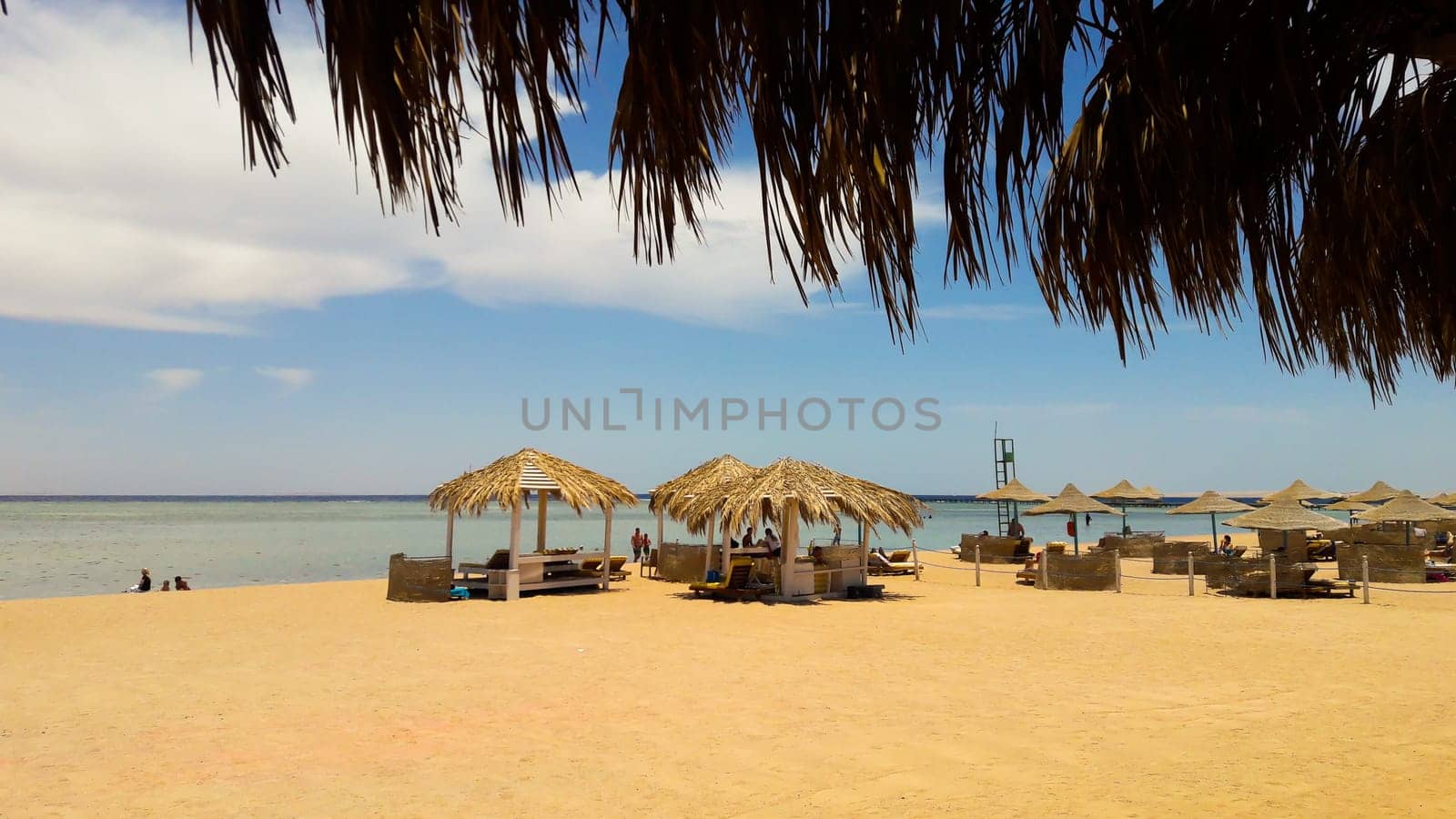 Sea coast with thatched umbrellas on a sandy beach. Seascape on the beach at the end of the holiday season. A great place to relax on the Red Sea in Sharm El Sheikh, Egypt