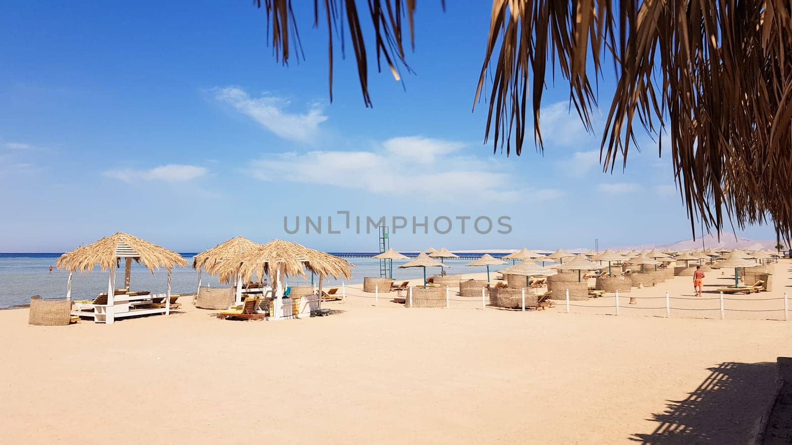 A beautiful tropical beach with thatched umbrellas on the shores of the Red Sea in Sharm El Sheikh. Summer landscape Beautiful sunny beach in Egypt. The concept of vacation, travel, vacation.