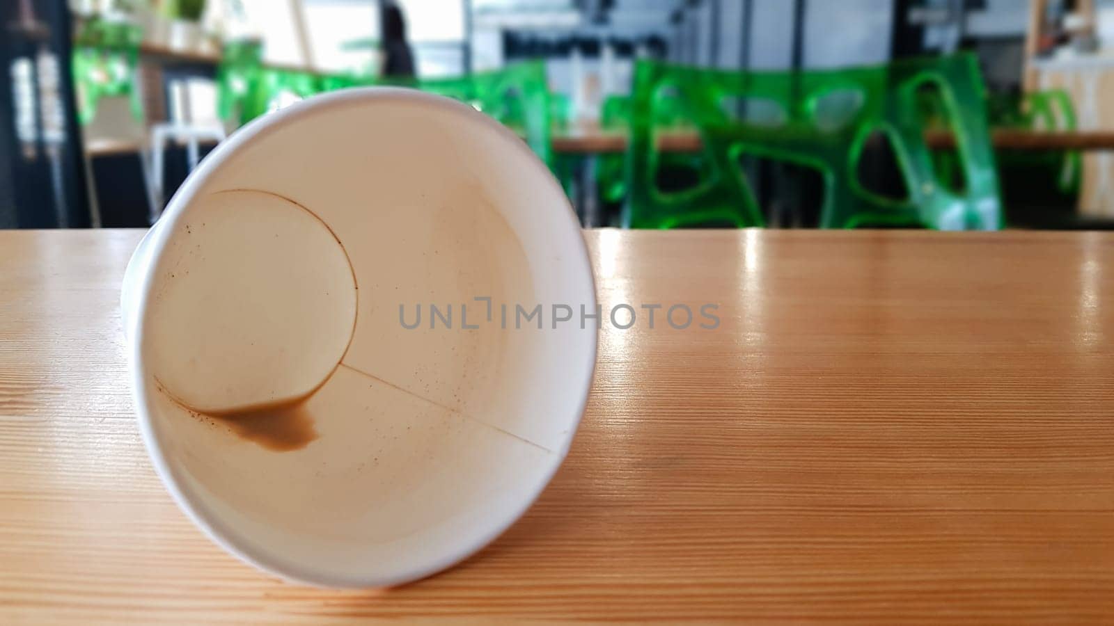 Paper white coffee cup disposable to take or go, on the wooden table of the coffee shop or dining room, place for a designer layout. Hot coffee cup in a cafe