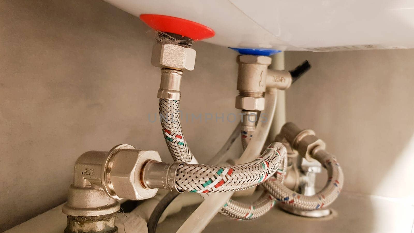 Connection of water supply, hot and cold water to the boiler. Hose for hot and cold water in the bathroom. Plumbing connections for a domestic electric water heater