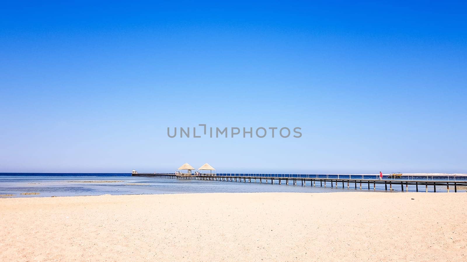 A beautiful sandy beach without people and a tropical blue sea with blue sky background