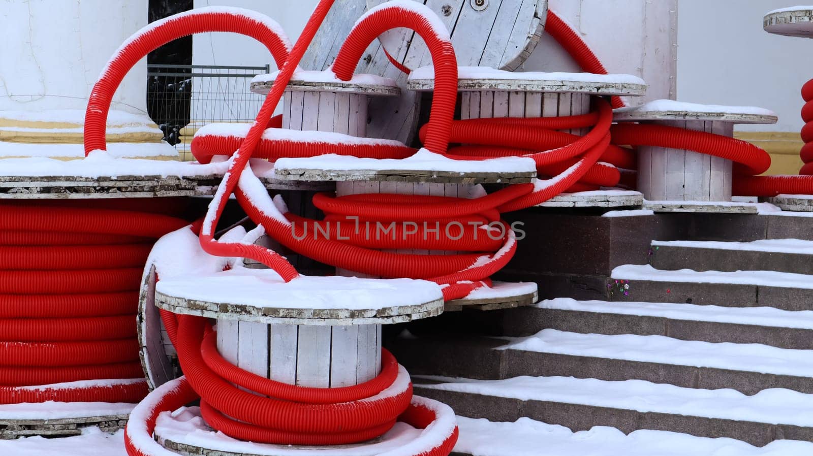 Large coils of red flexible corrugated pipe used to protect cables in electrical installations. Lots of colored polyethylene plastic hose used in construction for plumbing systems