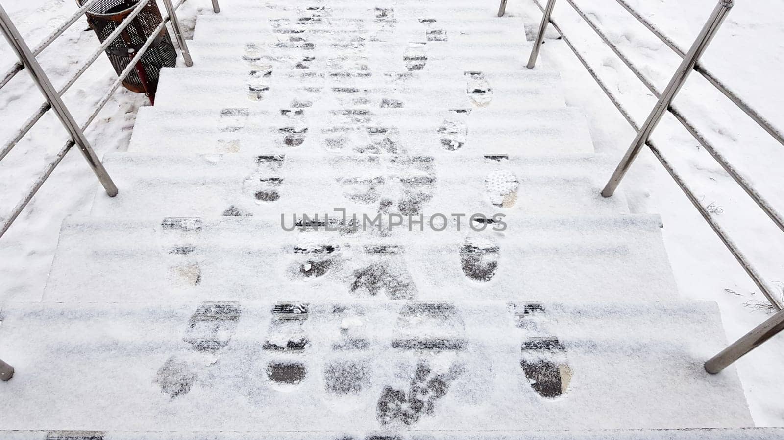 stair railings and snow. Slippery steps, ice covered with footprints, horizontal shot outside