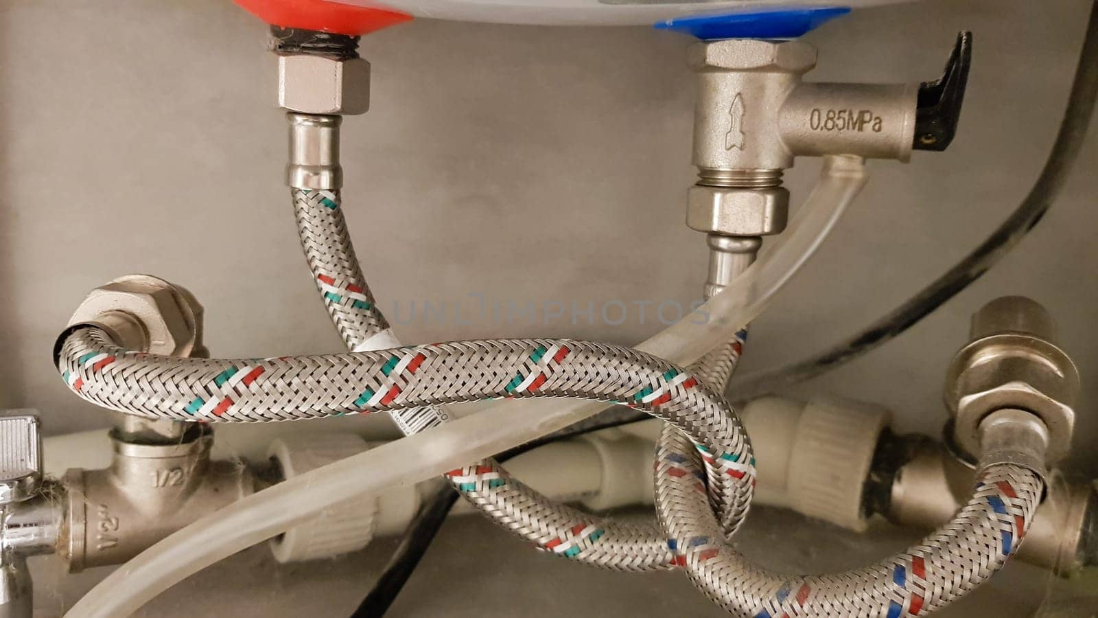 Connection of water supply, hot and cold water to the boiler. Hose for hot and cold water in the bathroom. Plumbing connections for a domestic electric water heater