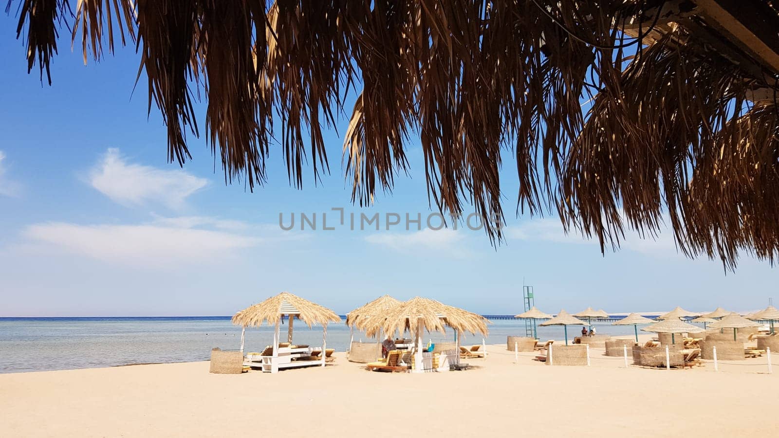 A beautiful tropical beach with thatched umbrellas on the shores of the Red Sea in Sharm El Sheikh. Summer landscape Beautiful sunny beach in Egypt. The concept of vacation, travel, vacation.