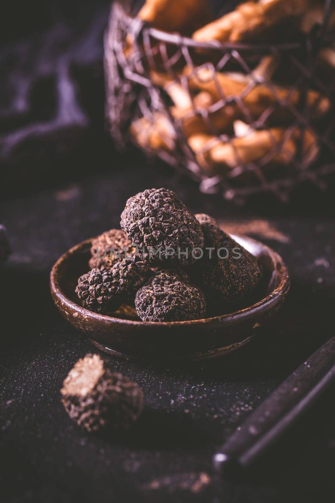 Black truffle in bowl on dark background, cooking delicacy