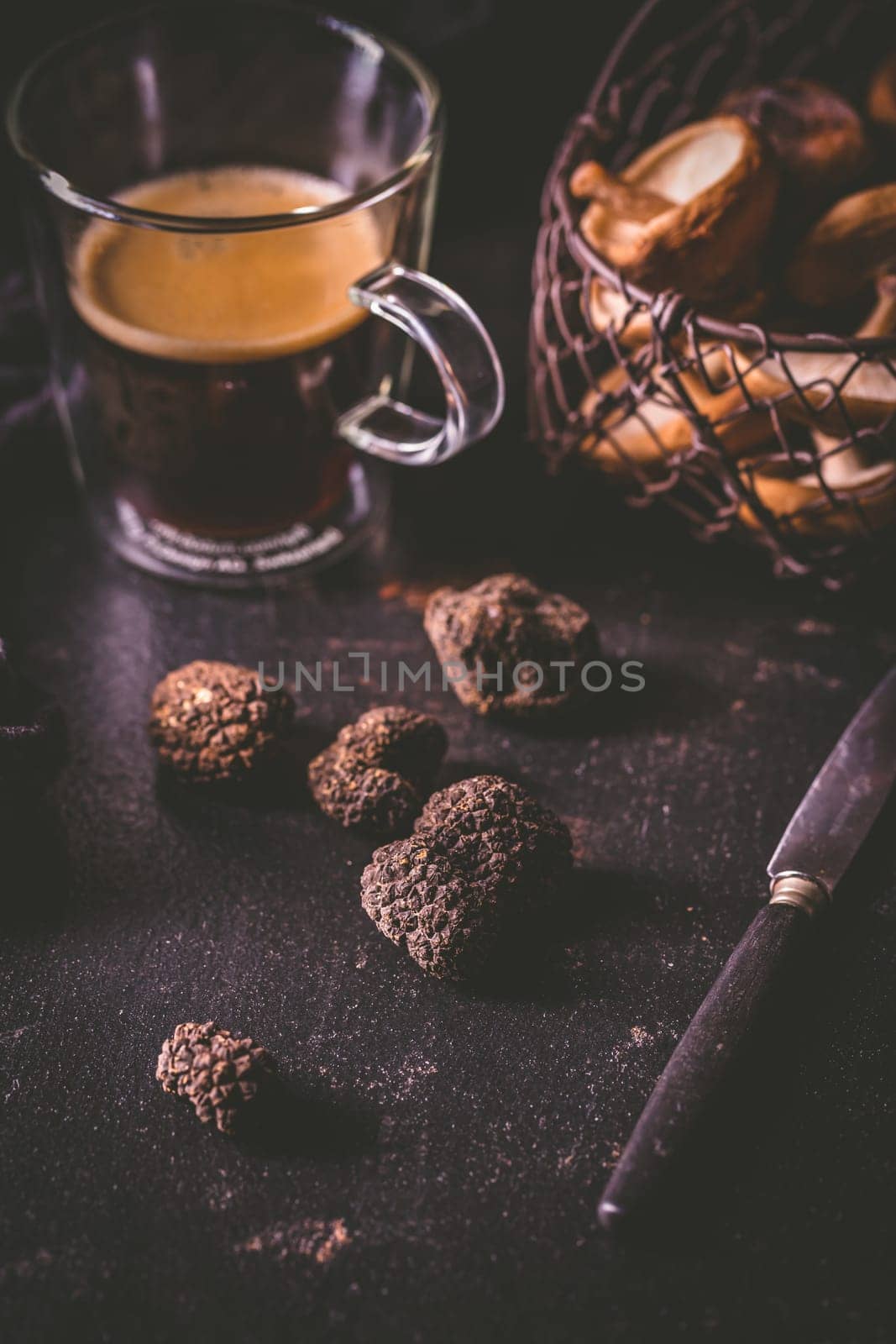 Black truffle on dark kitchen table with black coffee and mushrooms, cooking delicacy