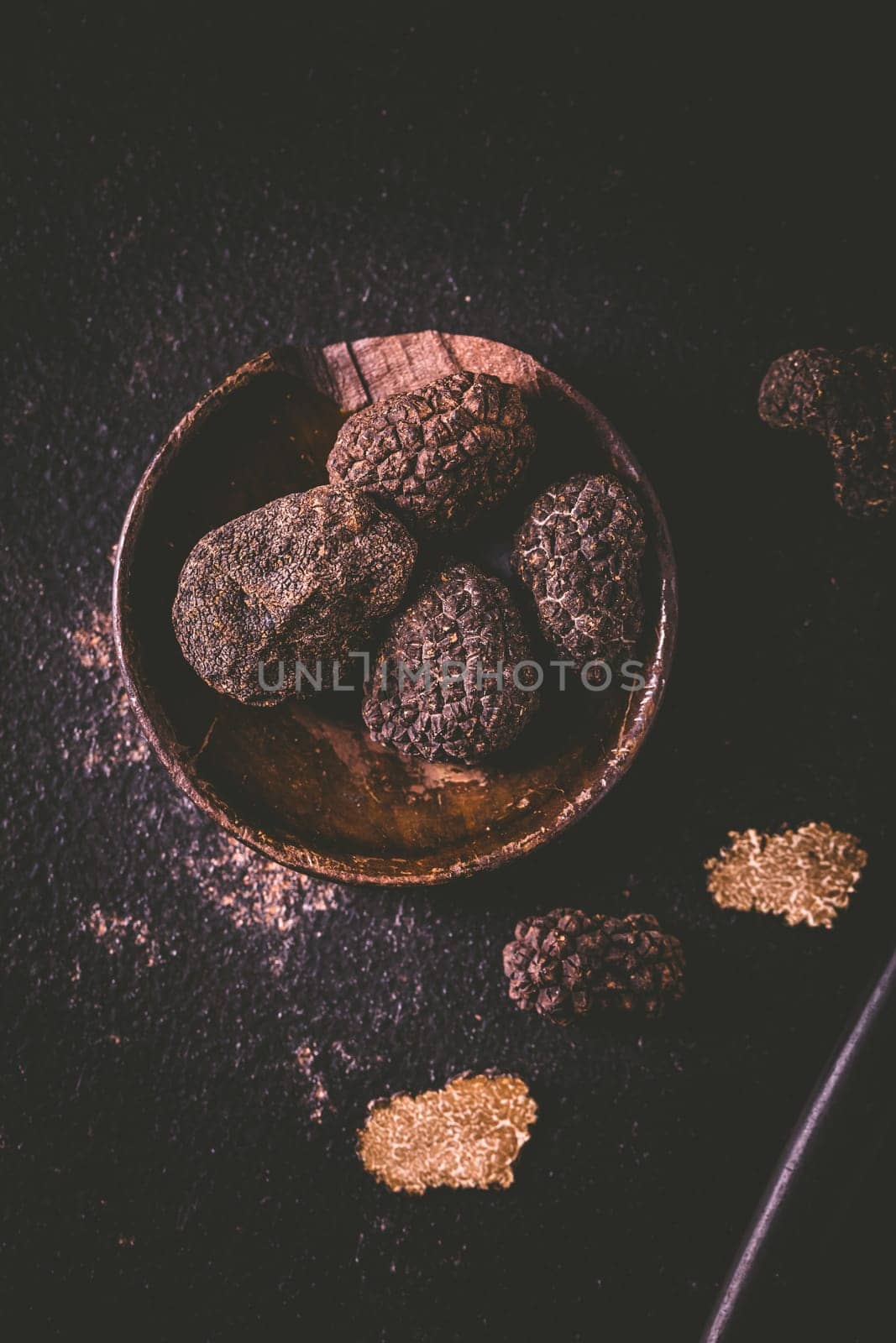 Black truffle in bowl on dark background, cooking delicacy