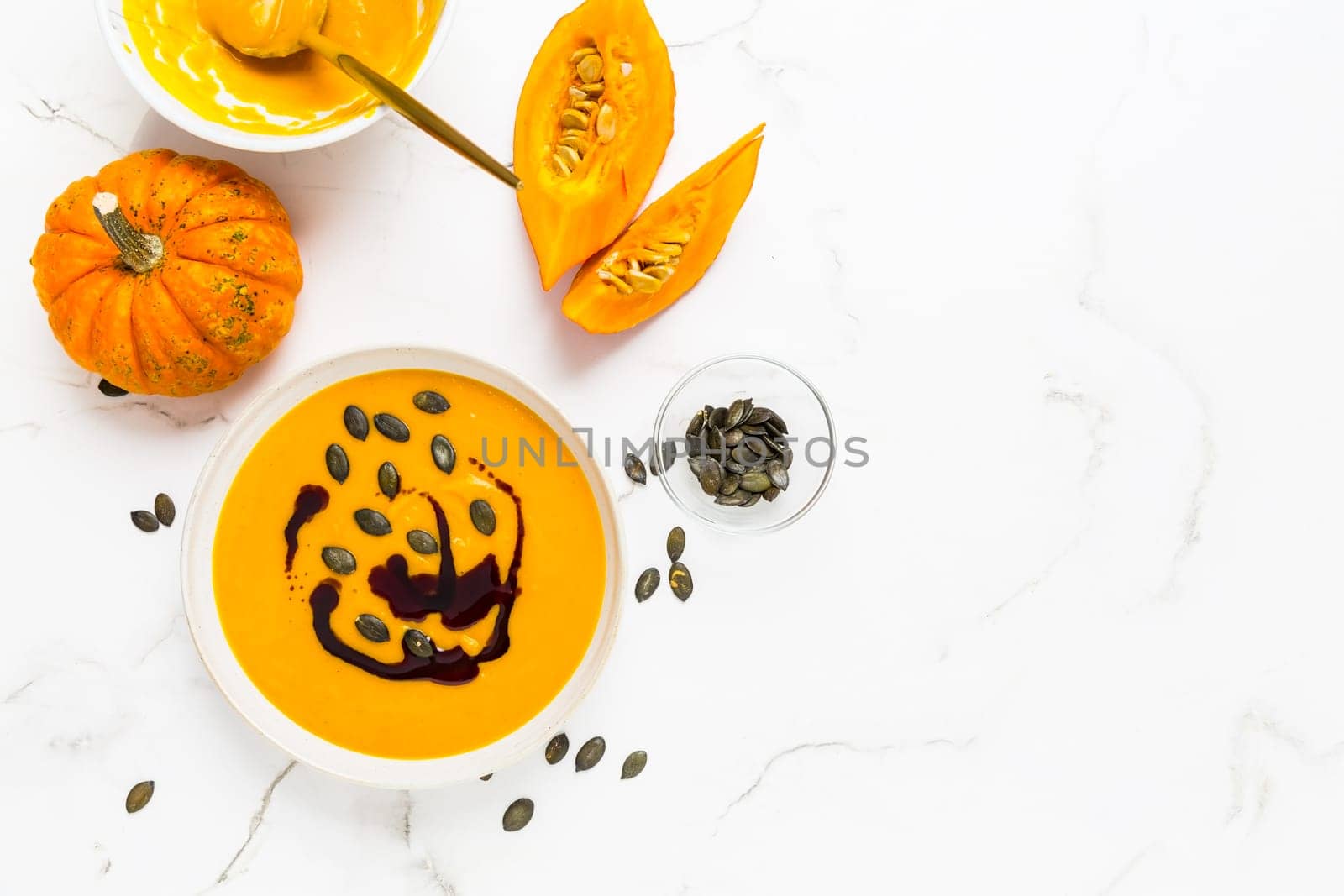 Homemade pumpkin soup with pumpkin oil and seeds on marble background