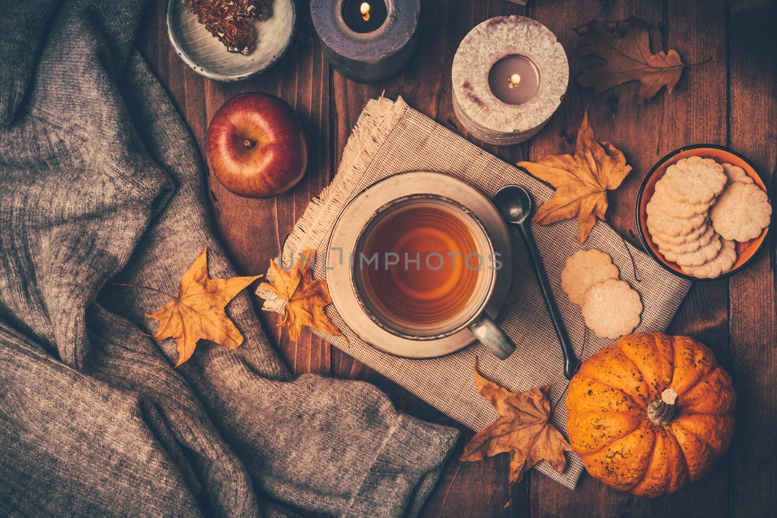 Hot tea with cookies, apple and fall foliage and pumpkins on wooden background