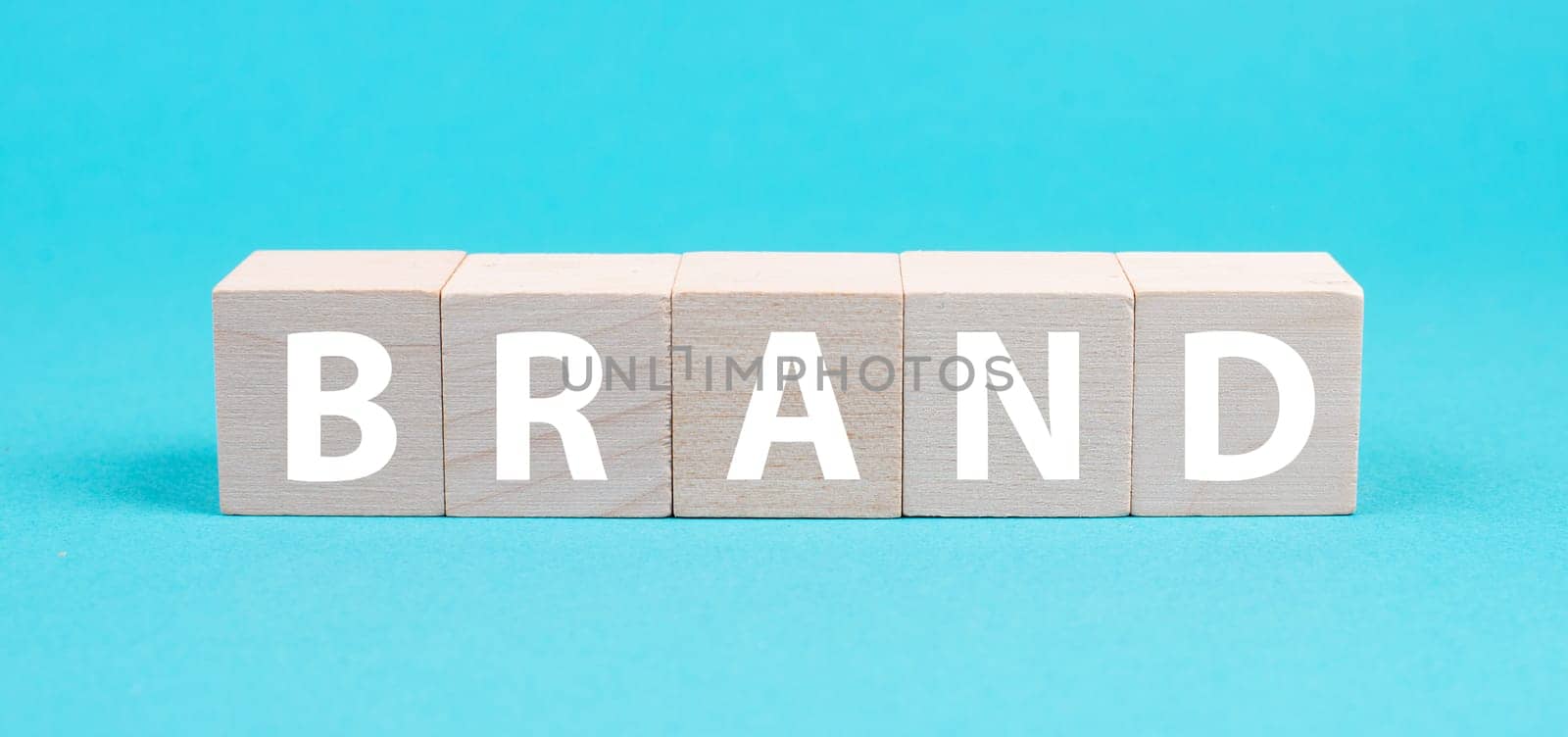 The word brand is standing on wooden cubes, positioning of a company, marketing, blue colored background
