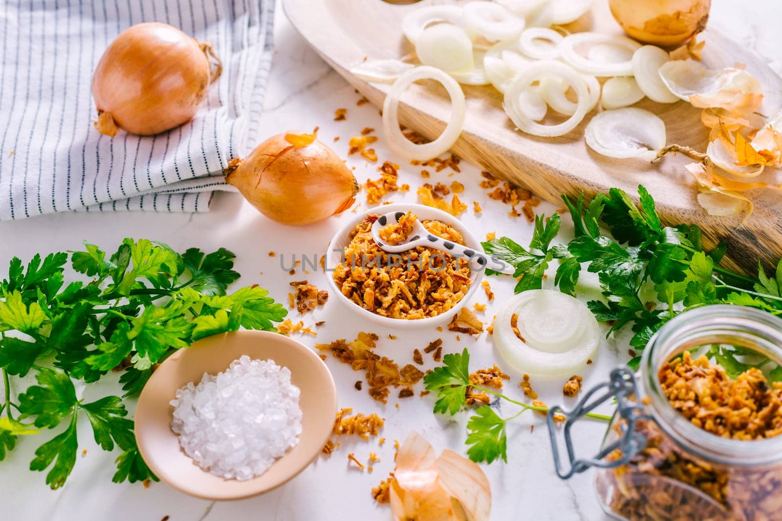Making homemade fried onions with ingredients on white kitchen table