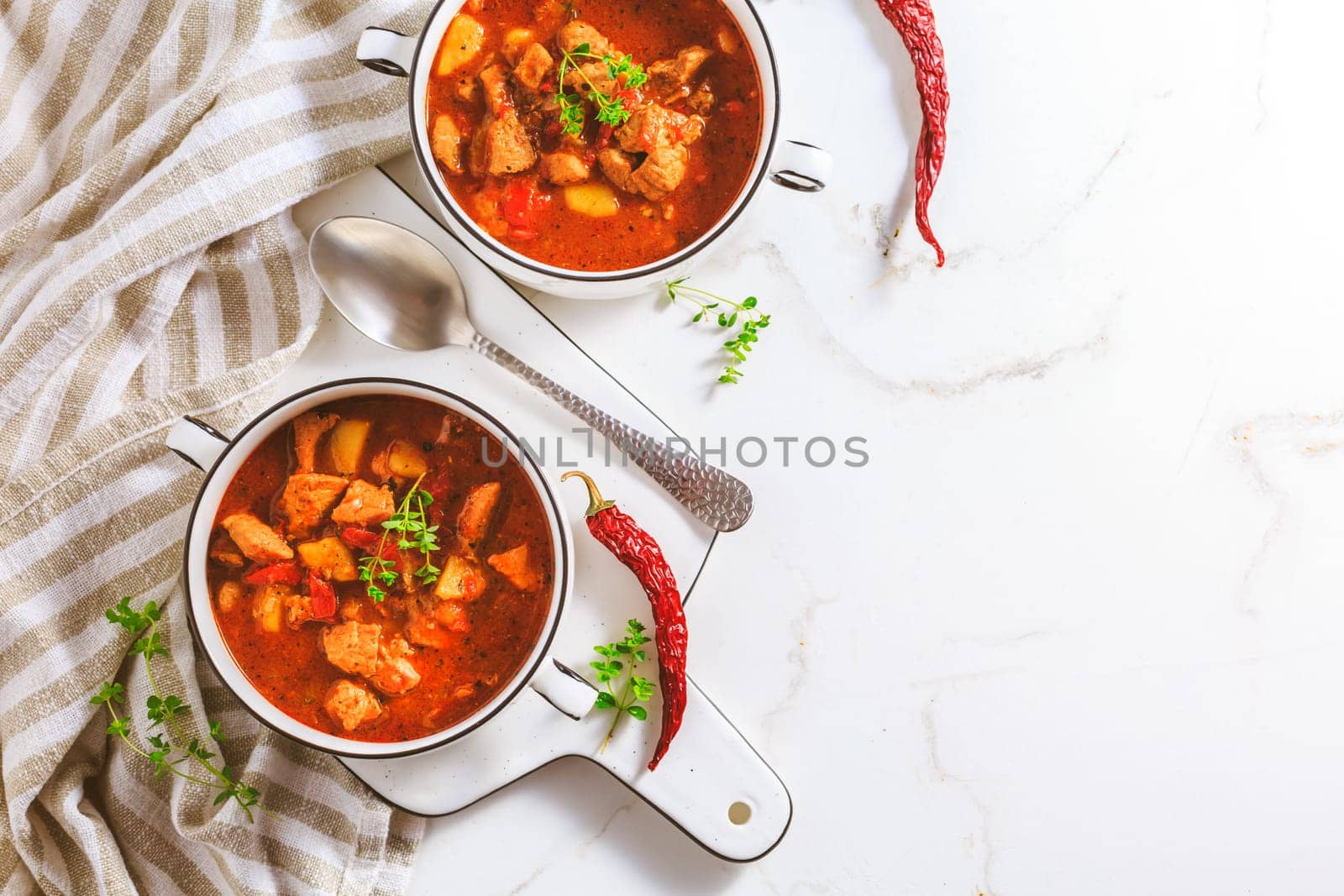 Beef goulash soup - hearty Hungarian soup of meat and vegetables seasoned with paprika on white background