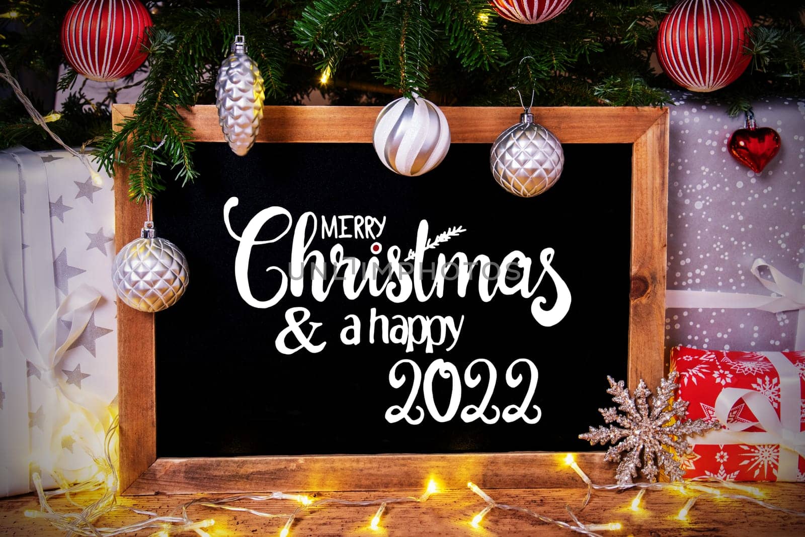 Blackboard With English Calligraphy Merry Christmas And Happy 2022. Christmas Tree With Ball, Gifts And Fairy Lights