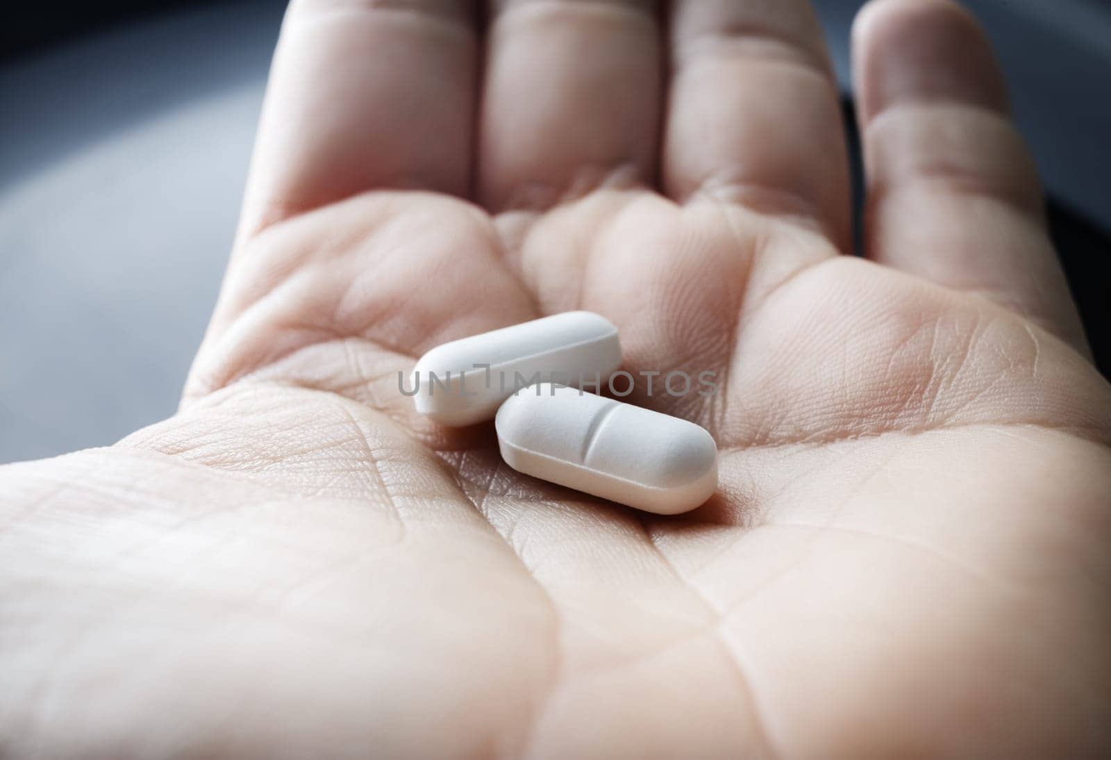 Close up of two pills in hand. Pharmaceutical medicaments.