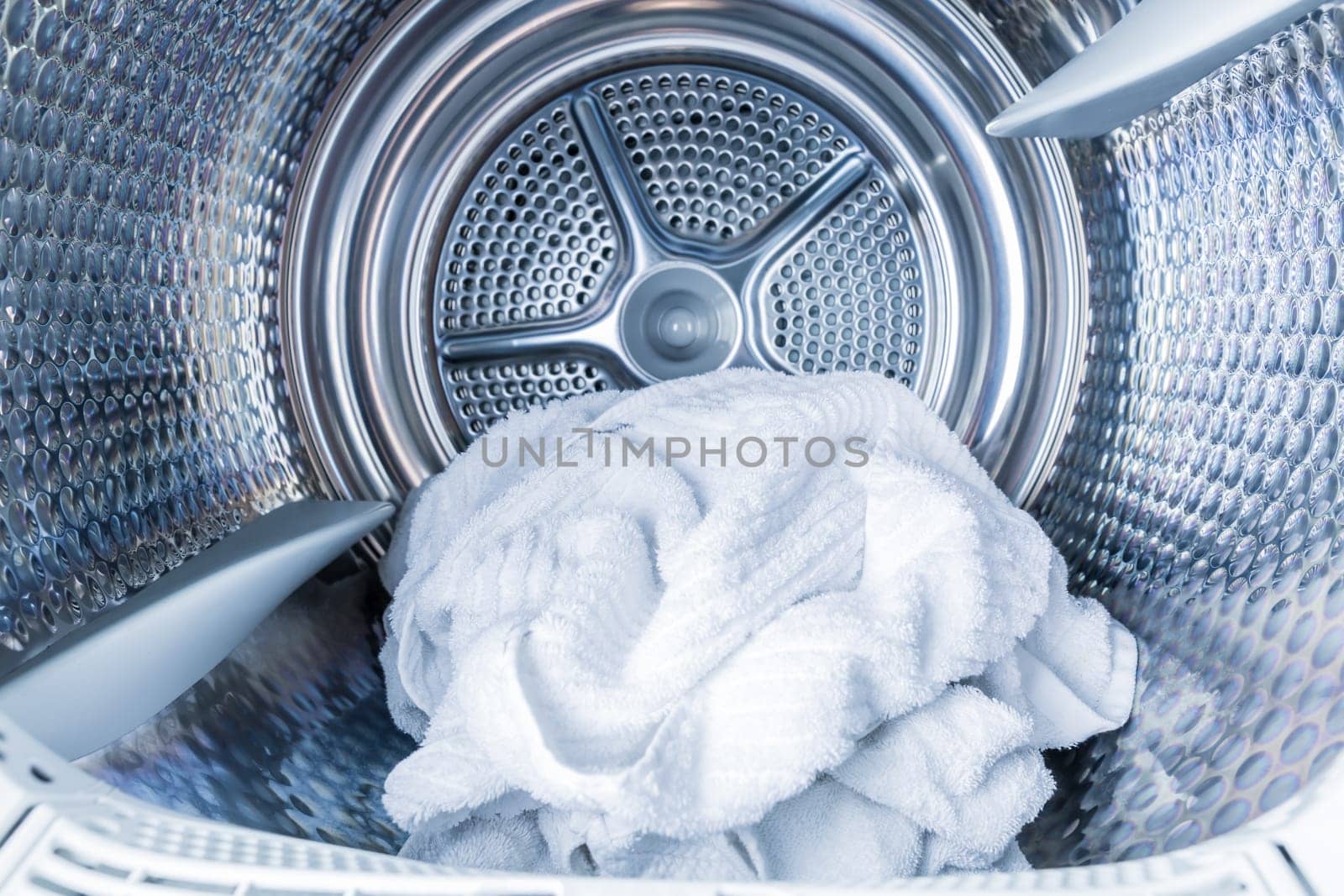 Inside of tumble dryer with clean white towels - new generation of dryer, household concept