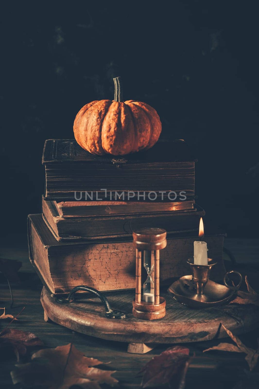Still life for Halloween and Thanksgiving with old books, pumpkins and candle on dark background