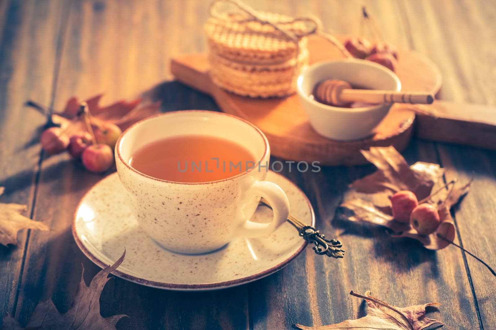 Hot tea with honey, homemade wafer biscuit and autumn leaves on wooden background