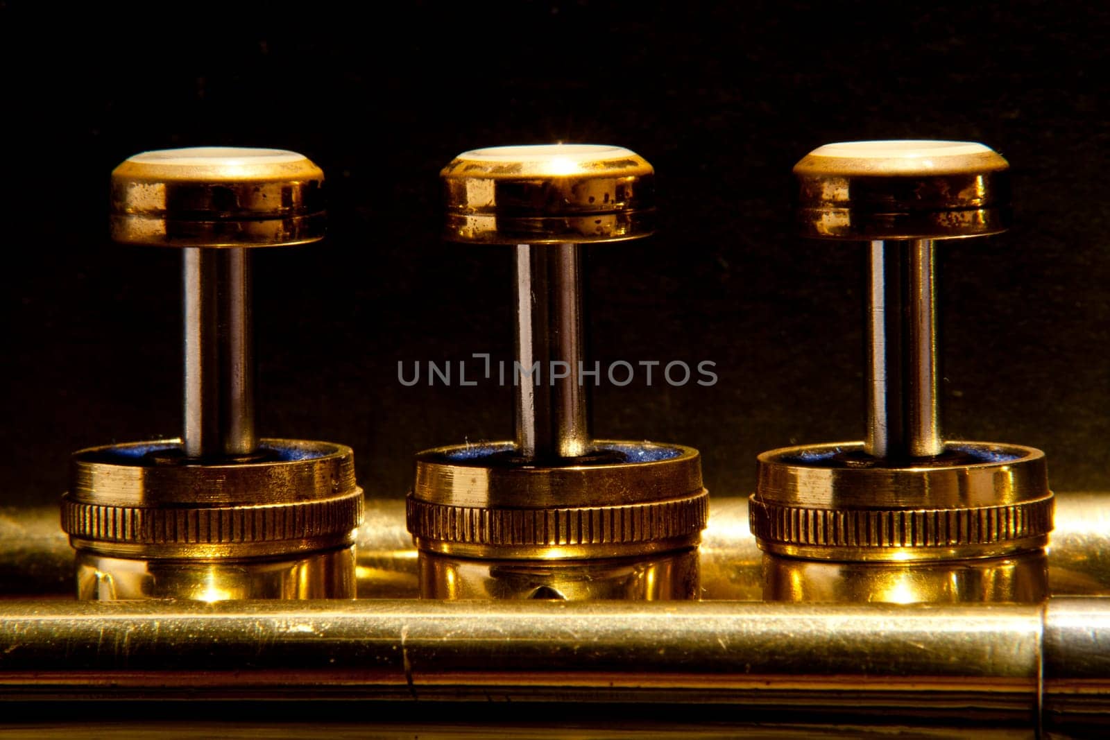 The valves on a trumpet in a line