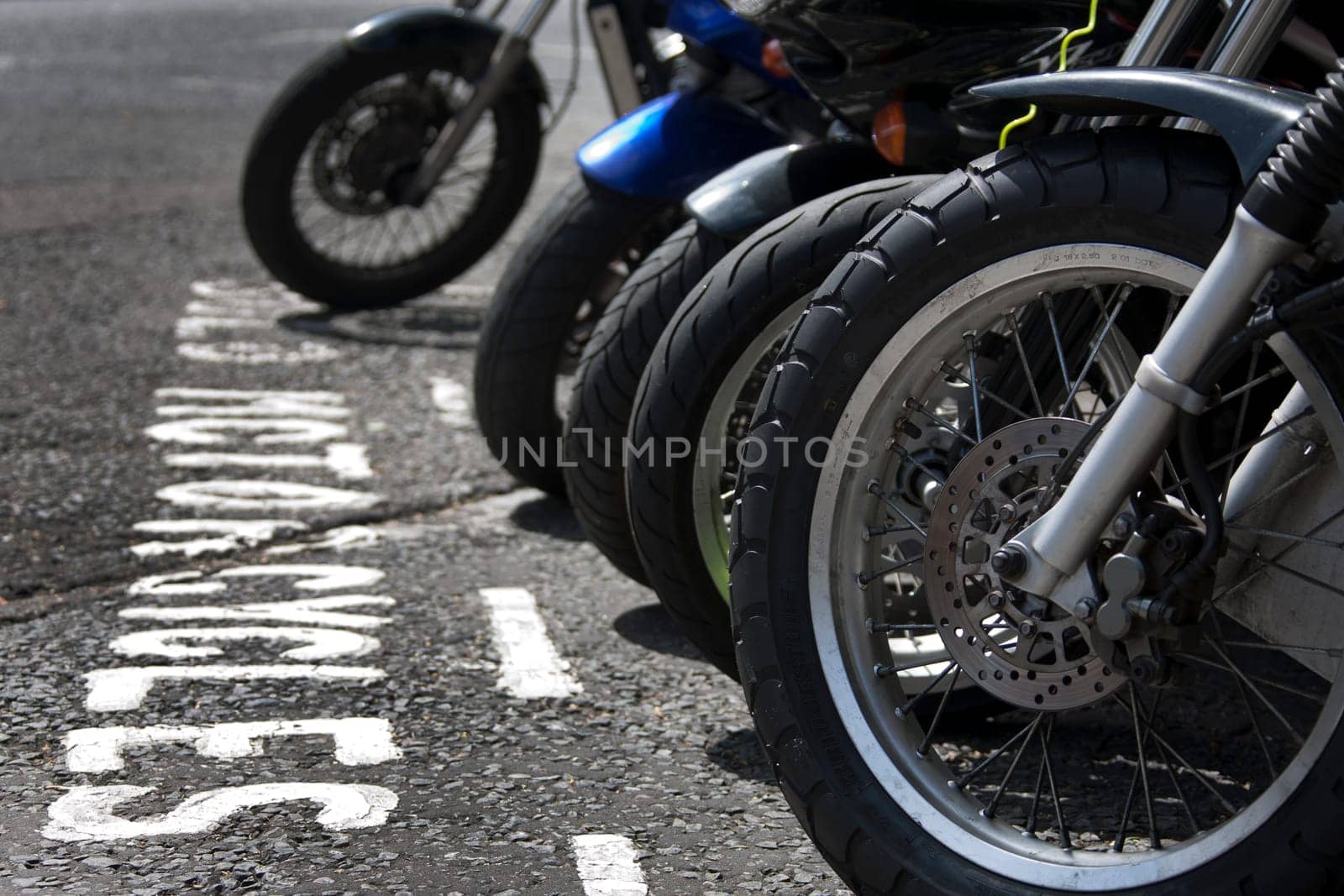 The front wheels of motorcycles parked in a bay