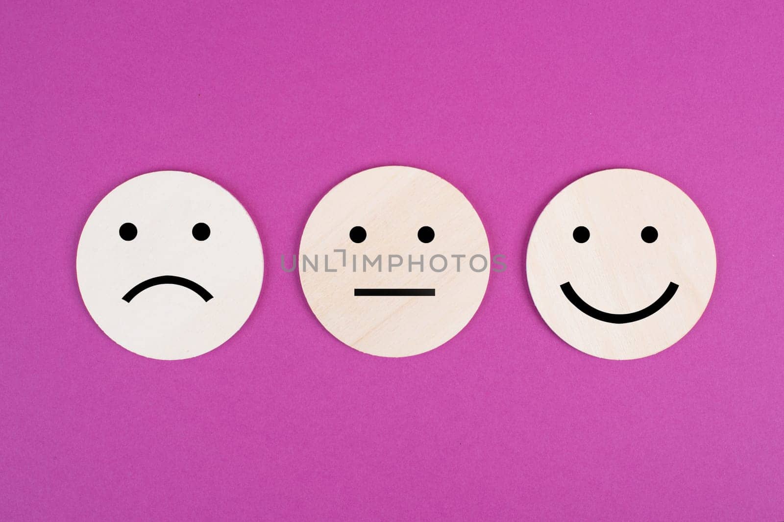 Three faces, smiling, sad in different colors on a pink background, copy space, rating, communication, customer feedback