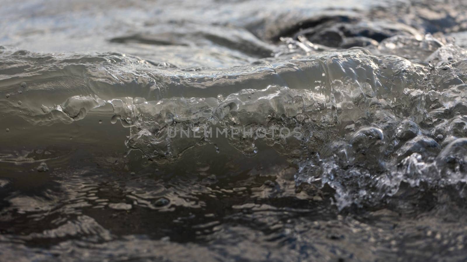 Wallpaper of floating water with sunlight with copy space. Waves in ocean in close up like background. Blue sea splashing in environment with sapce for text.
