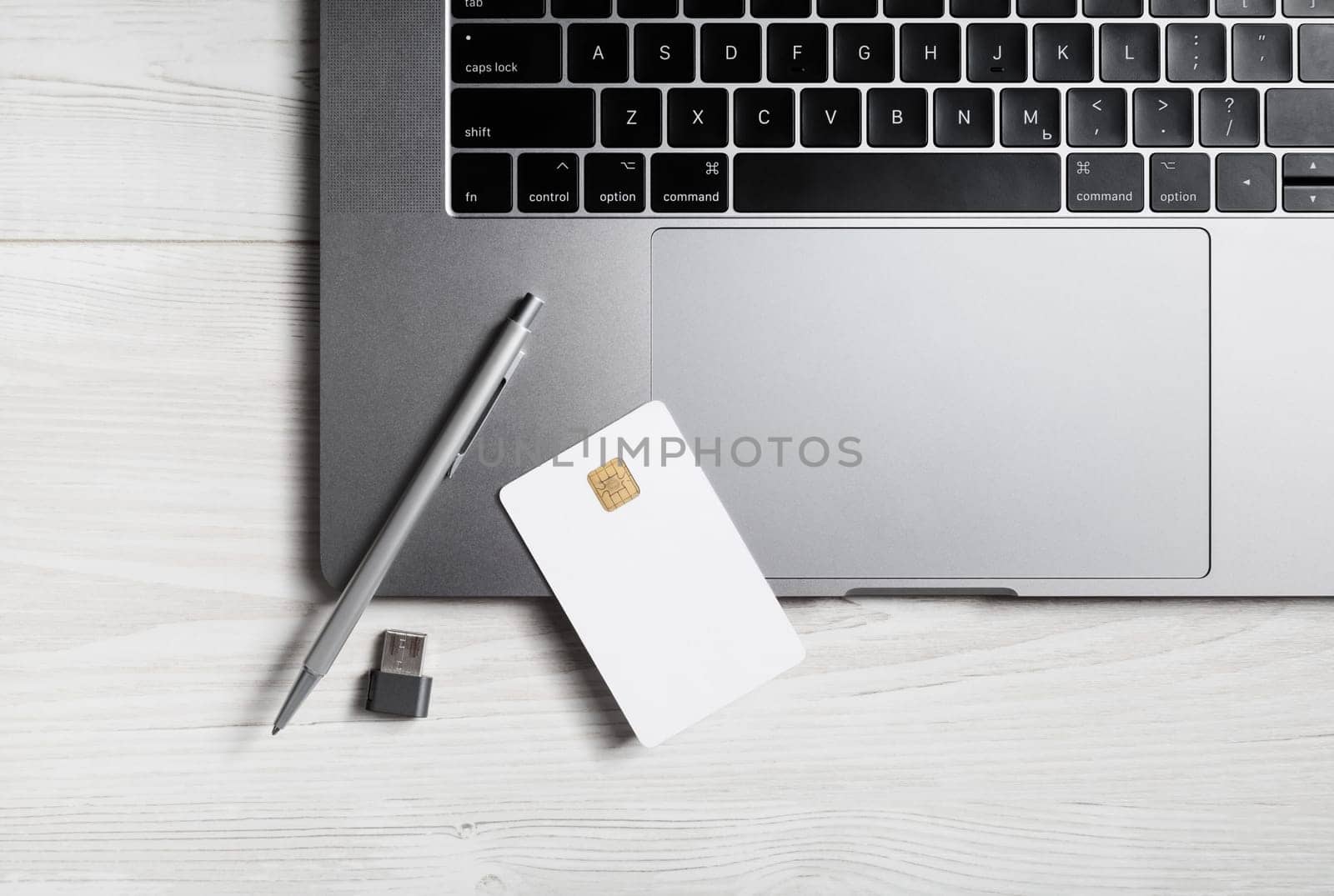 Online business concept. Blank bank card, pen, flash drive and laptop keyboard.