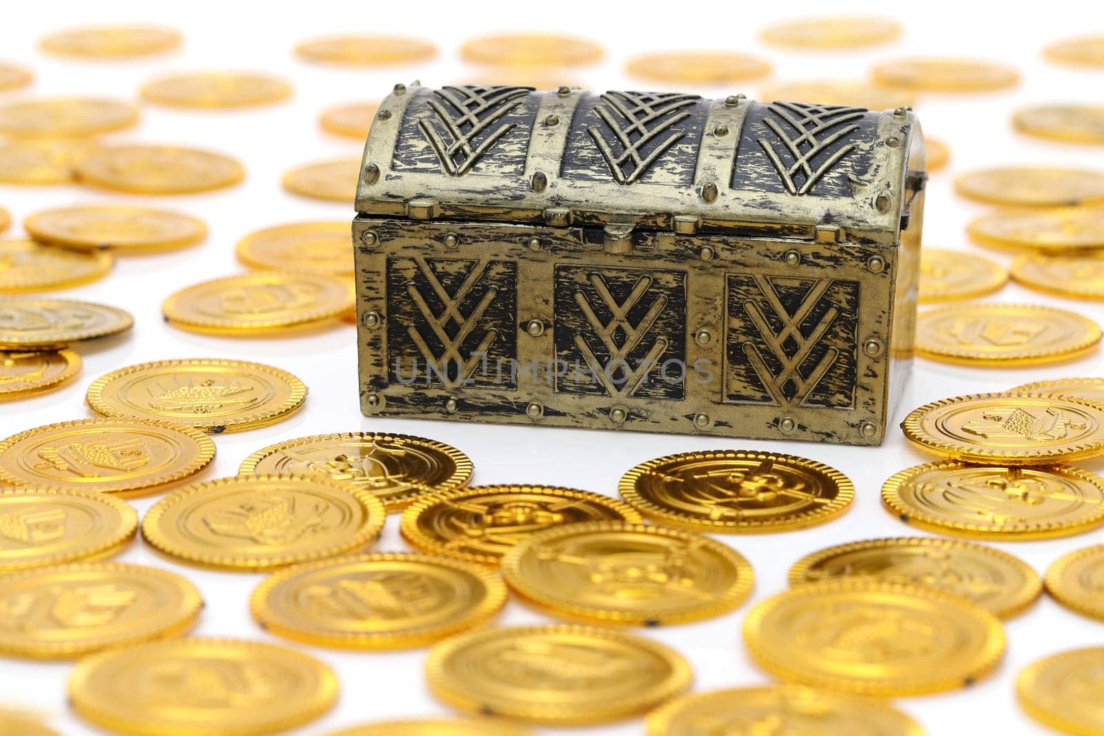 Closed treasure chest with gold colored coins on white background